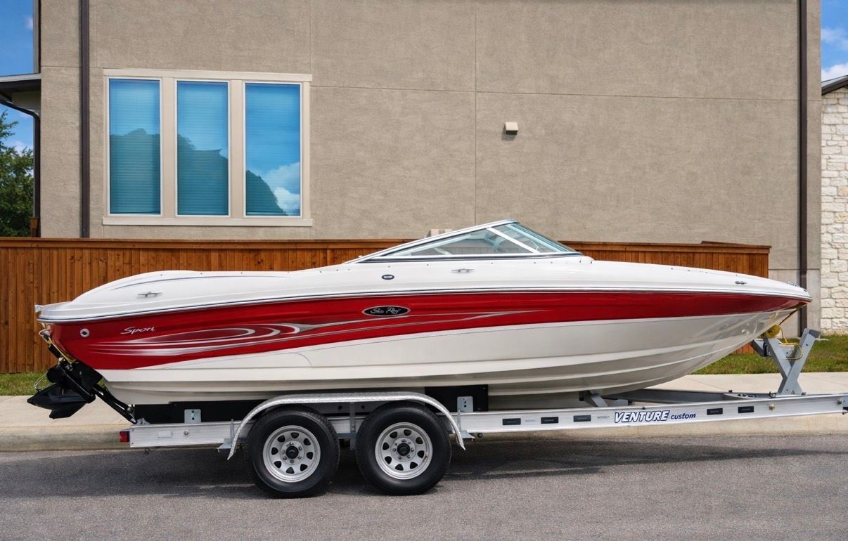 2005 Sea Ray 200 Sport boat on trailer in front of house.