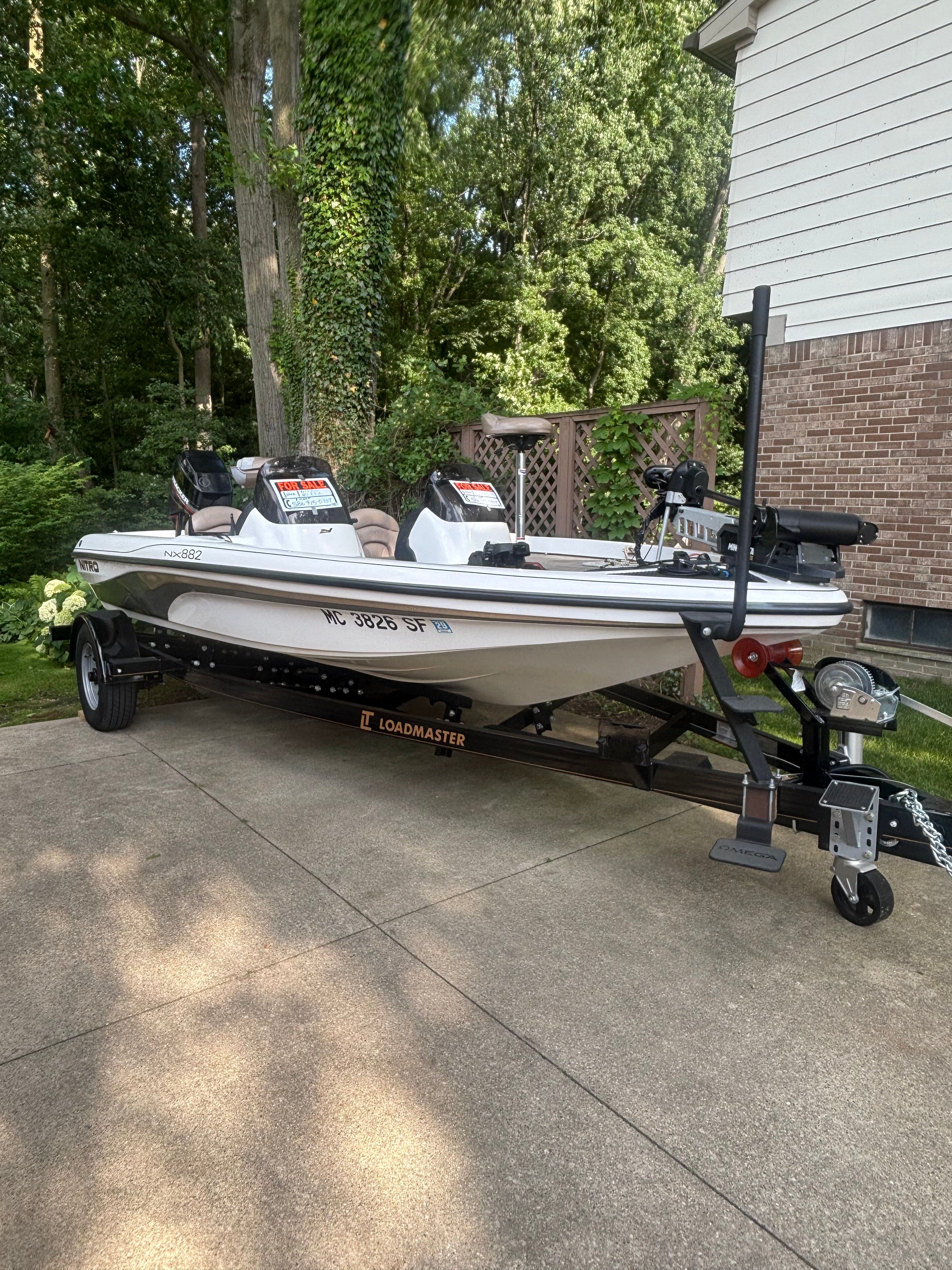 A white 2002 Nitro NX 882 boat is on a trailer in a driveway.