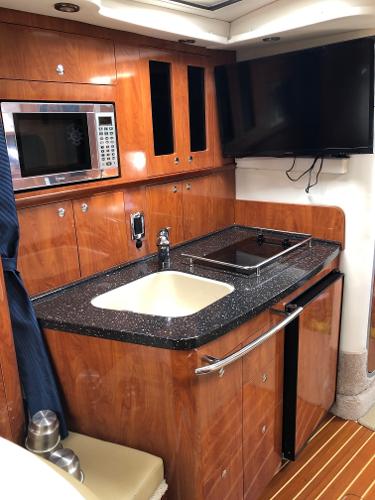 Galley of a 2008 Four Winns V338 with microwave, sink, and TV.