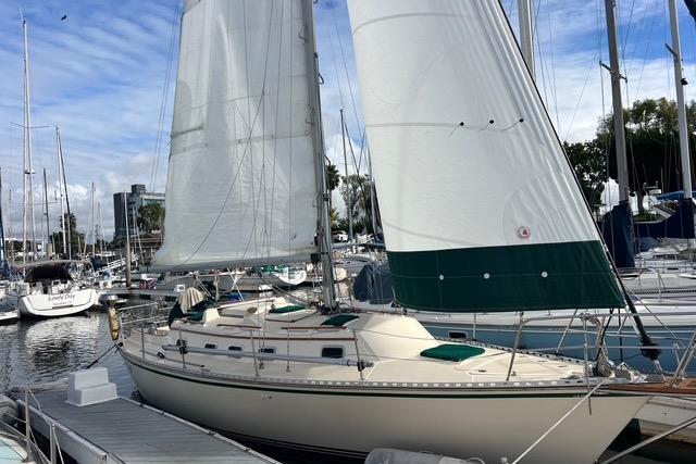 Sailboat docked at marina, 1991 Caliber 33 model, with white sails and green accents.