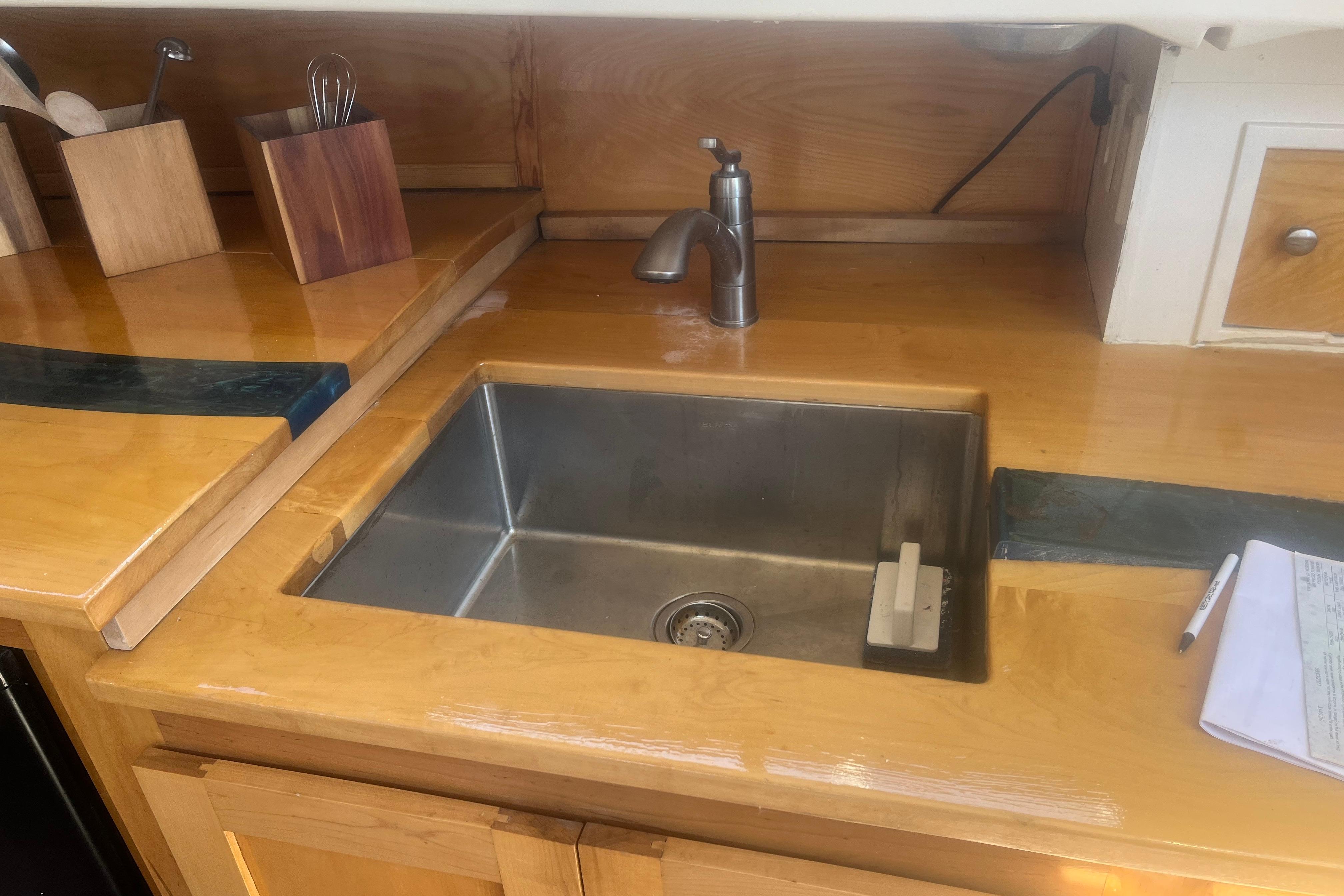 Wooden boat kitchen with stainless steel sink, faucet, and countertop accessories, C&C 30, 1972.