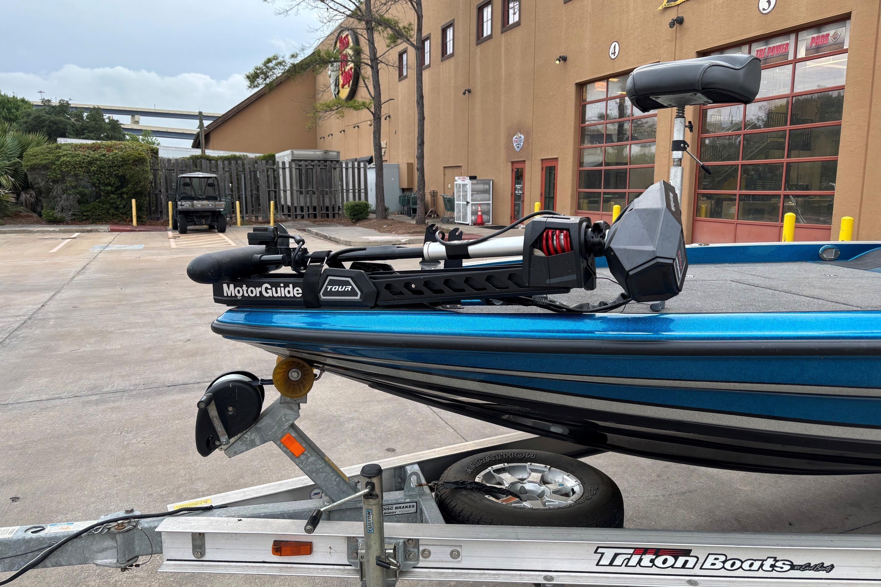2009 Triton 22 TrX boat with MotorGuide Tour motor on trailer, parked outdoors.