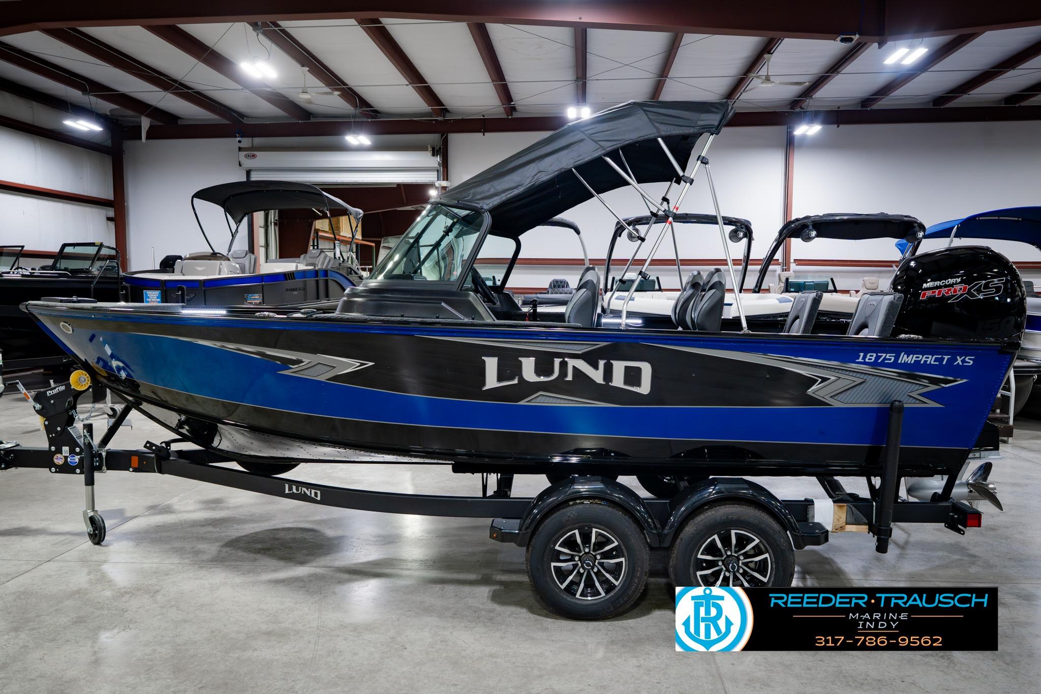 2026 Lund 1875 Impact XS boat in showroom, featuring sleek blue and black design.