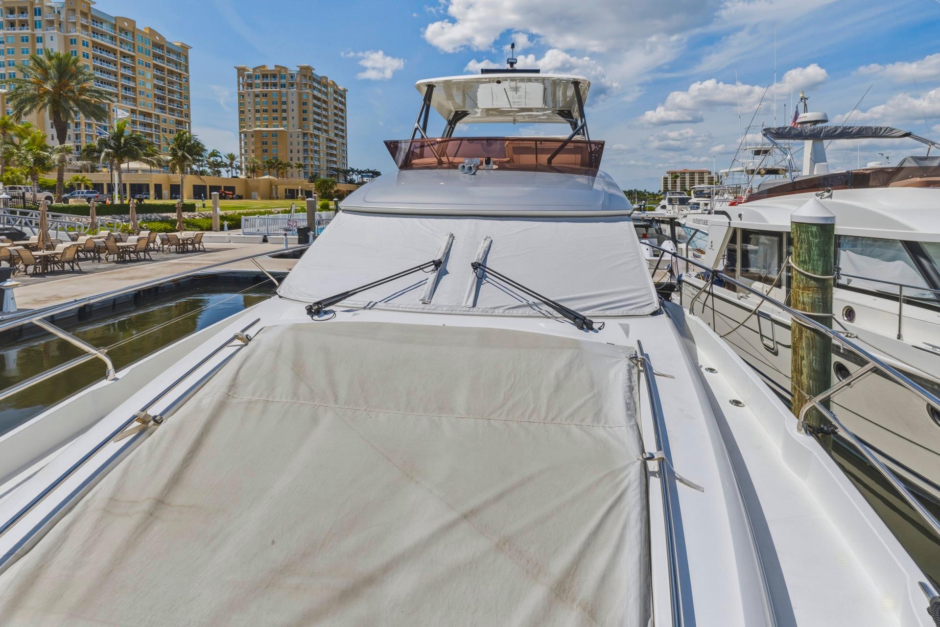 Luxury 2022 Prestige 520 yacht docked at marina with modern buildings in background.