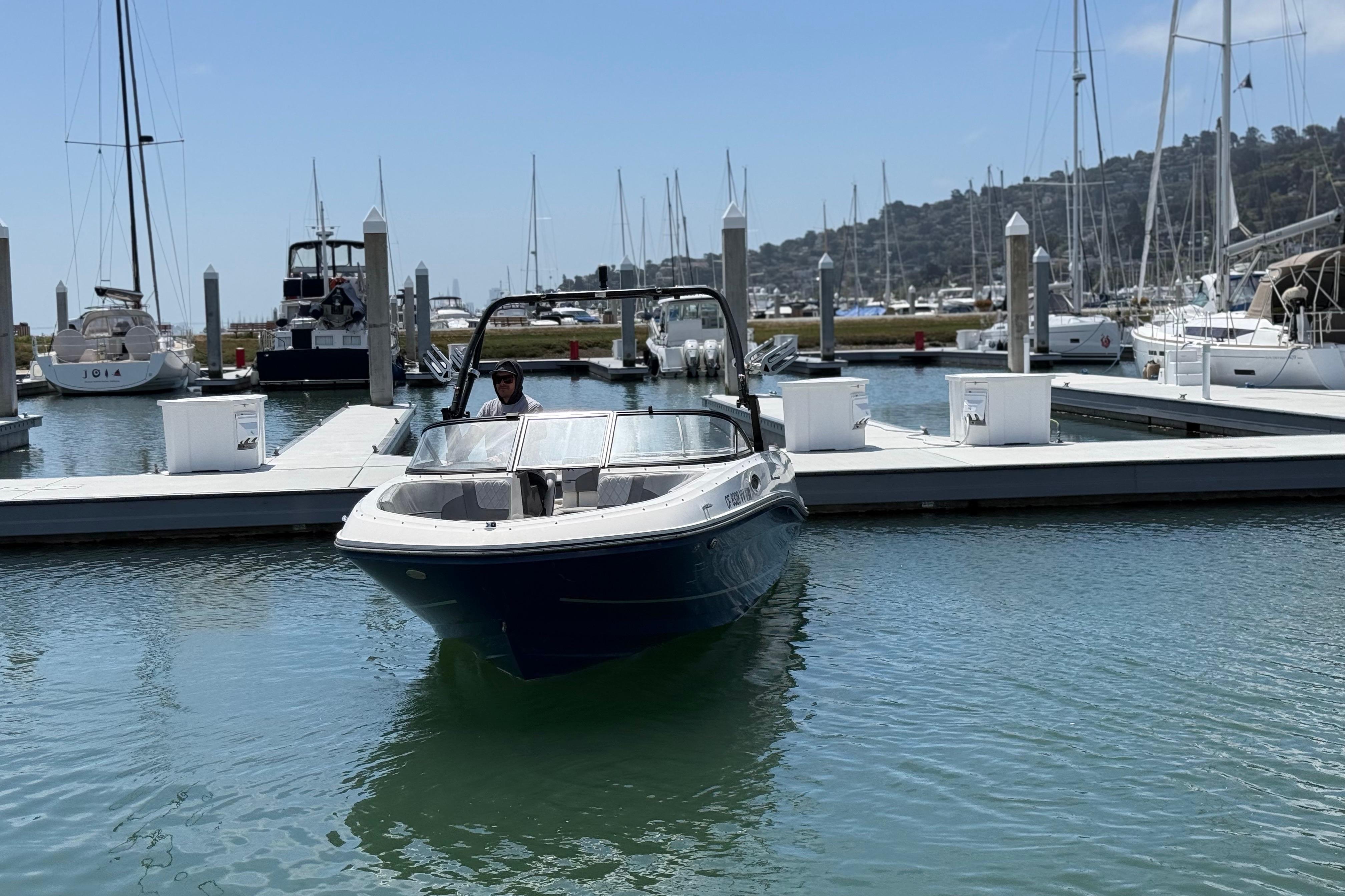 2021 Bayliner VR5 Bowrider I/O docked at a marina with sailboats in the background.