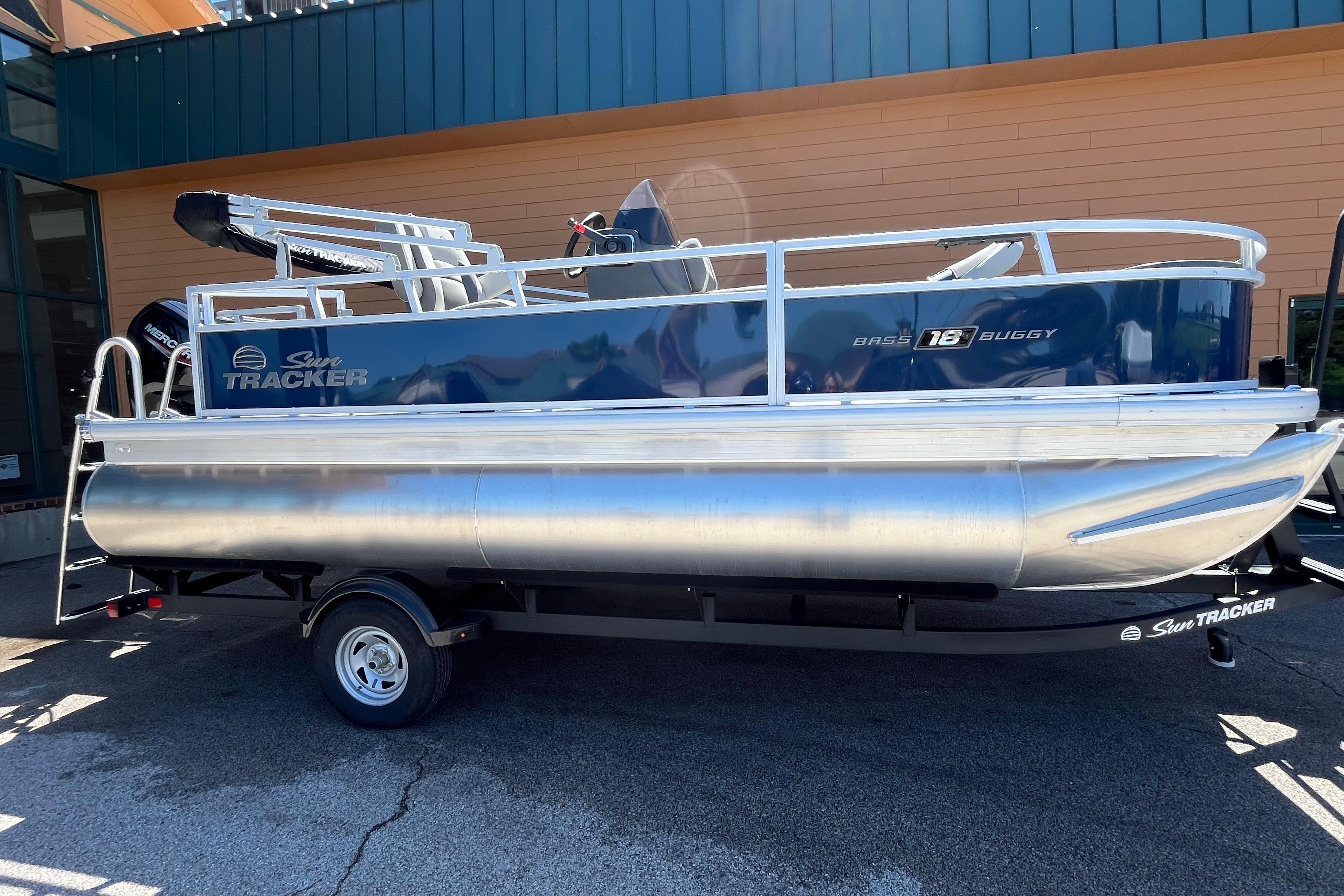 2026 Sun Tracker Bass Buggy 18 DLX pontoon boat on trailer, parked outdoors.