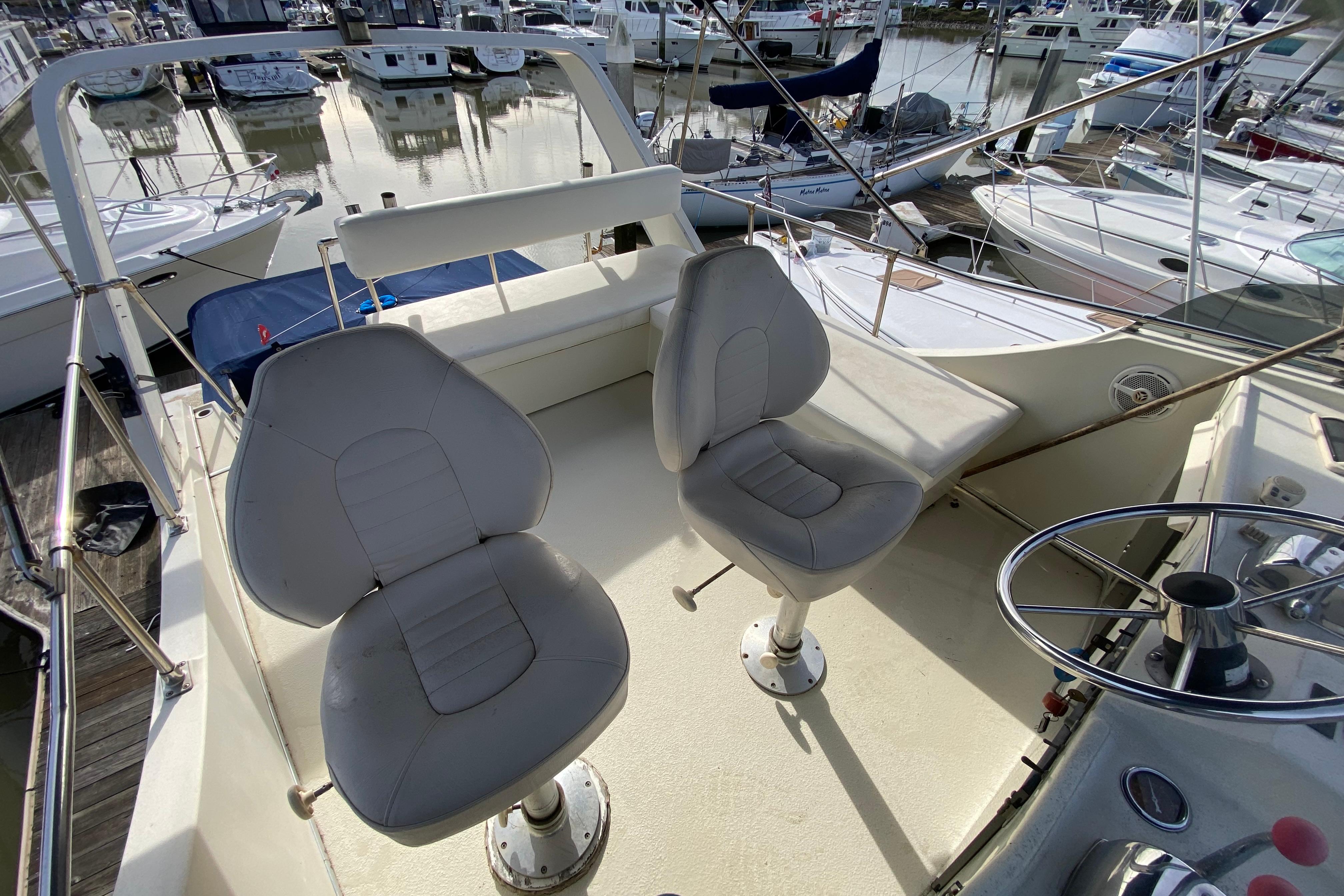 1986 Tollycraft Flybridge Convertible with dual seats and steering wheel, docked at marina.