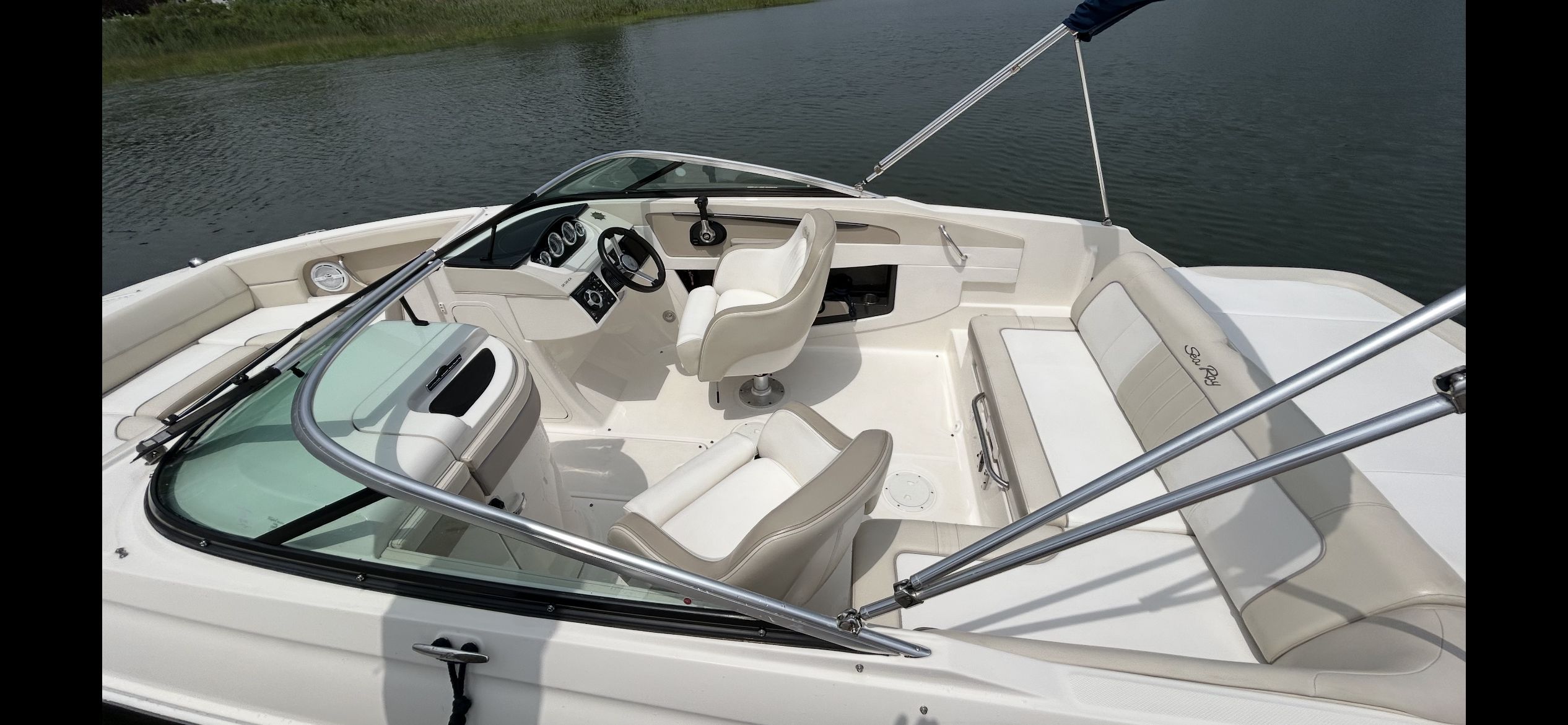 The image shows a 2013 Sea Ray 220 Sundeck boat on the water. It features white seating and a modern cockpit.