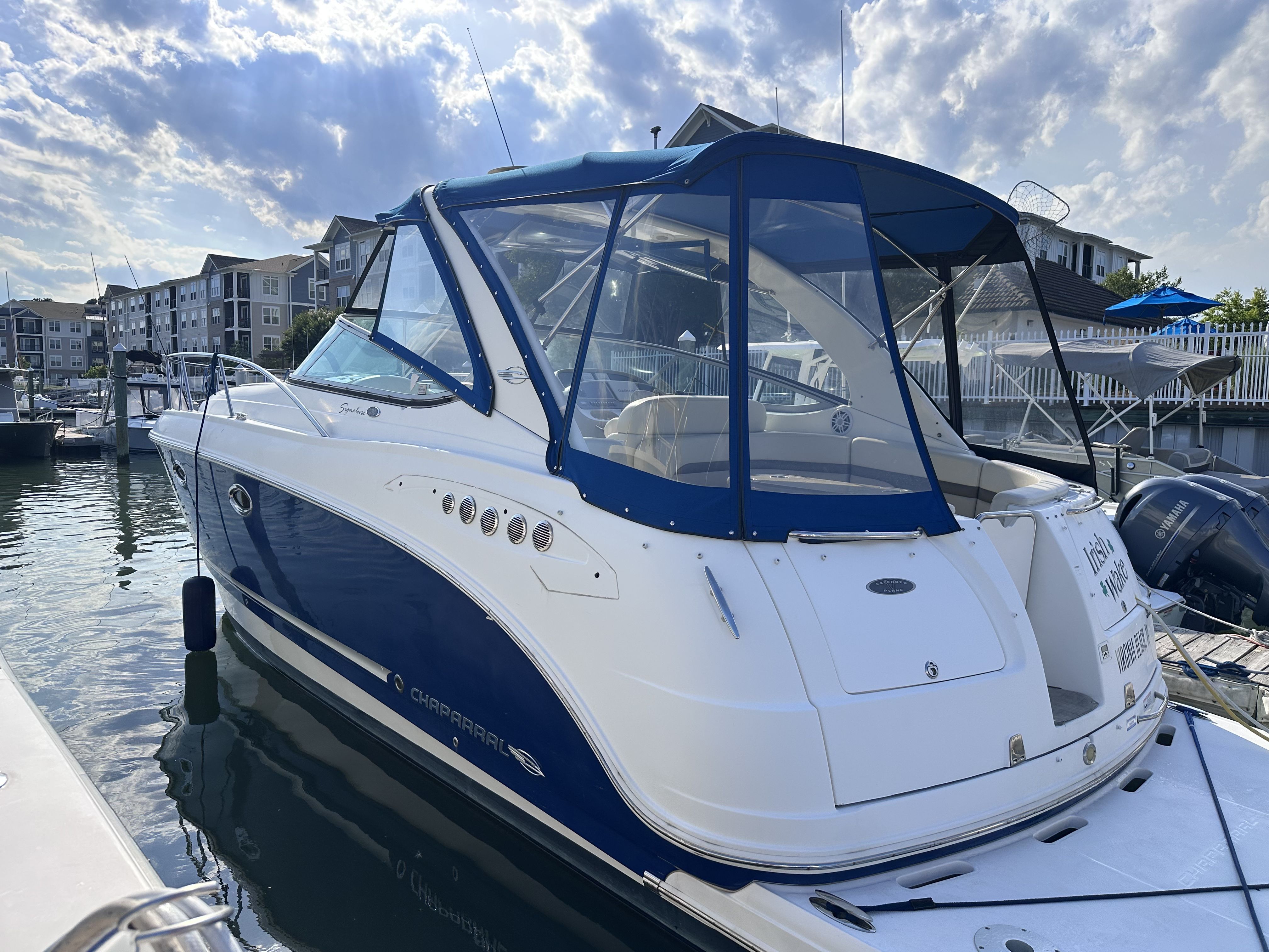 2008 Chaparral Signature 330 docked, featuring a blue canopy and sleek white exterior.