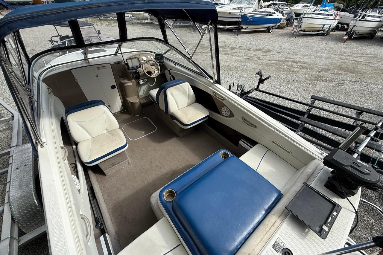 2005 Bayliner 210 Discovery boat interior with blue and white seating, parked in a marina.