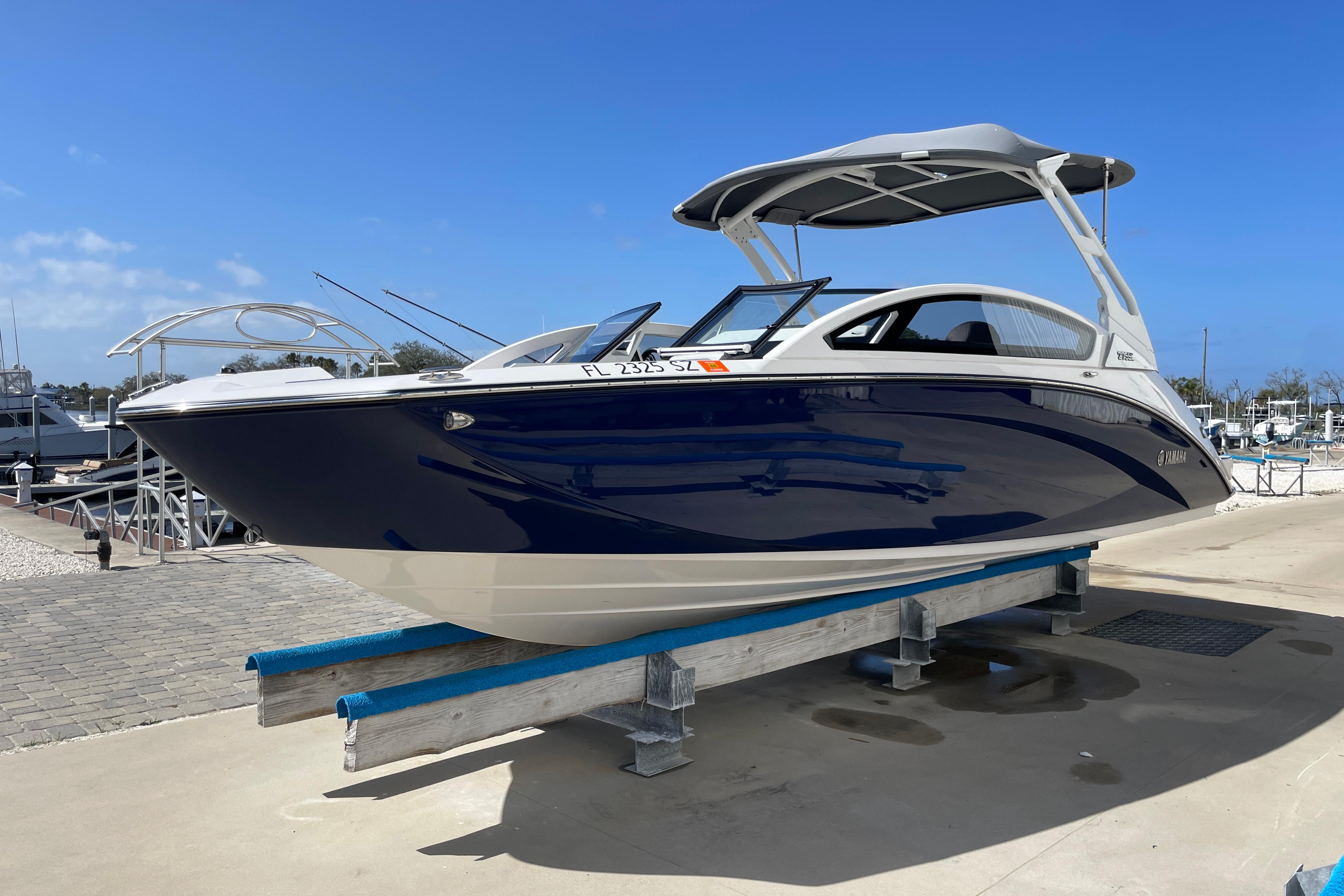 2021 Yamaha Boats 275SE on display at a marina, featuring sleek blue and white design.