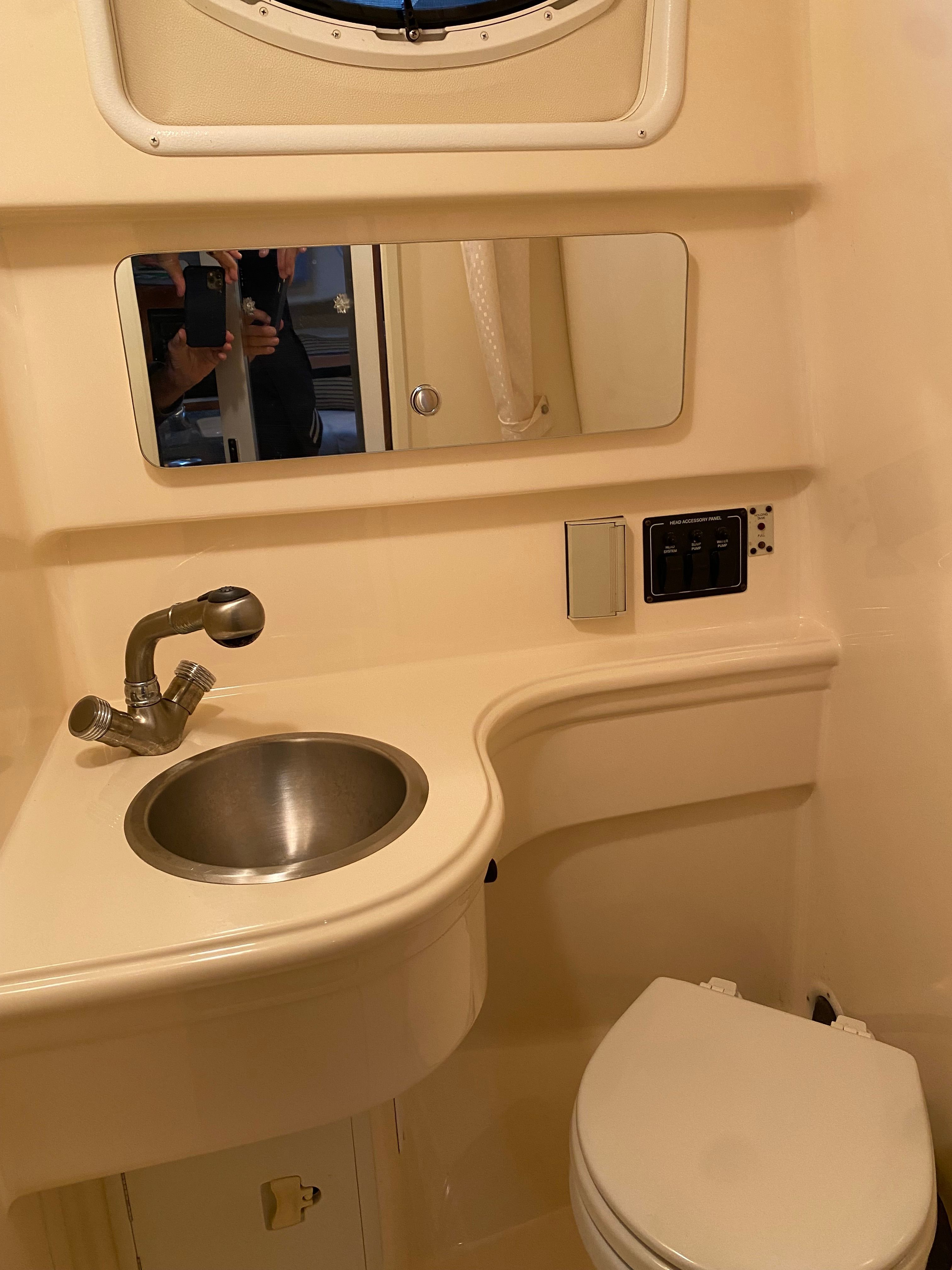 The image shows a boat bathroom with a sink, mirror, and toilet.