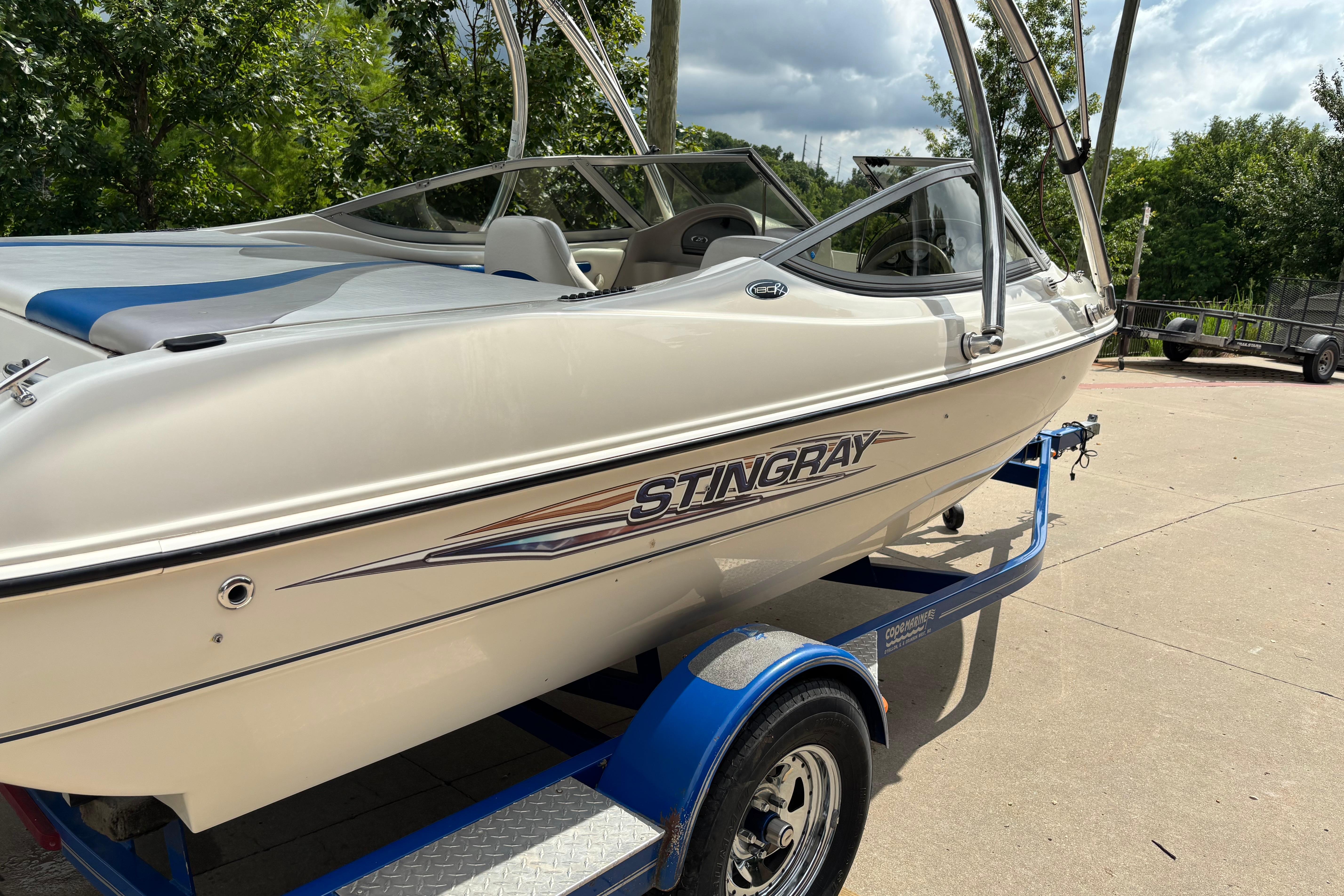 2007 Stingray 180 RX boat on trailer, parked outdoors with trees in background.