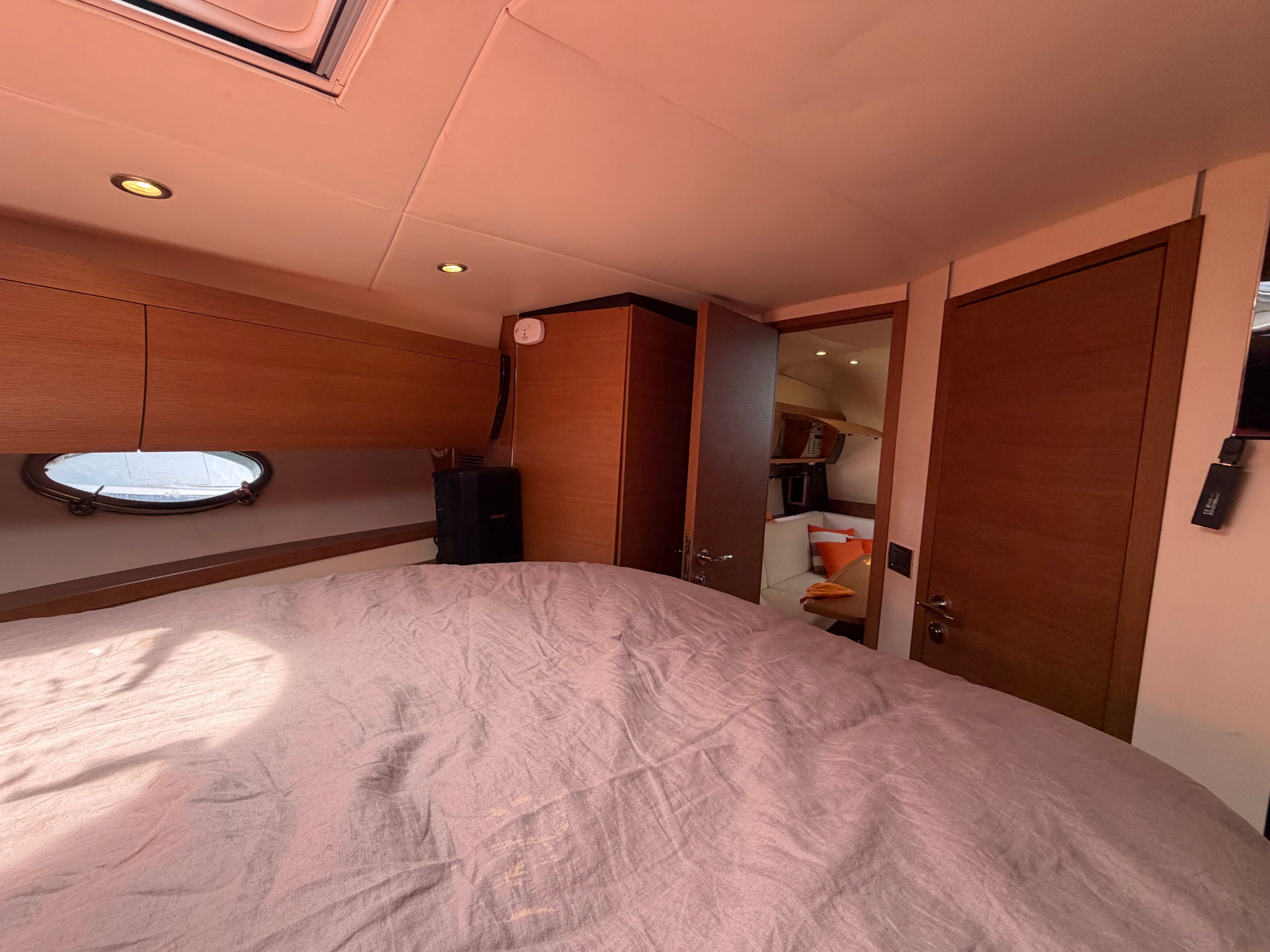 Interior of a 2011 Azimut Atlantis 40 with wooden furnishings and a porthole.