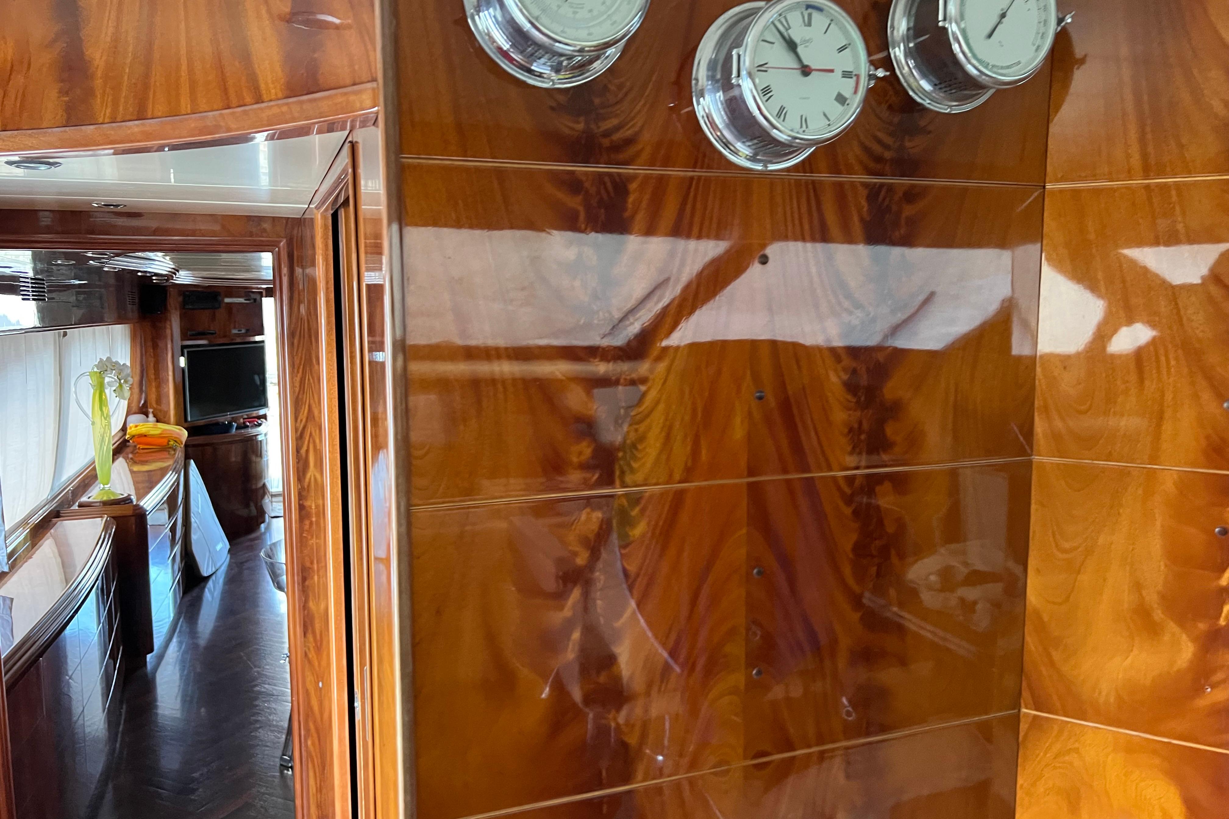Luxurious Maiora 24 yacht interior with polished wood paneling and nautical clocks, 2001 model.