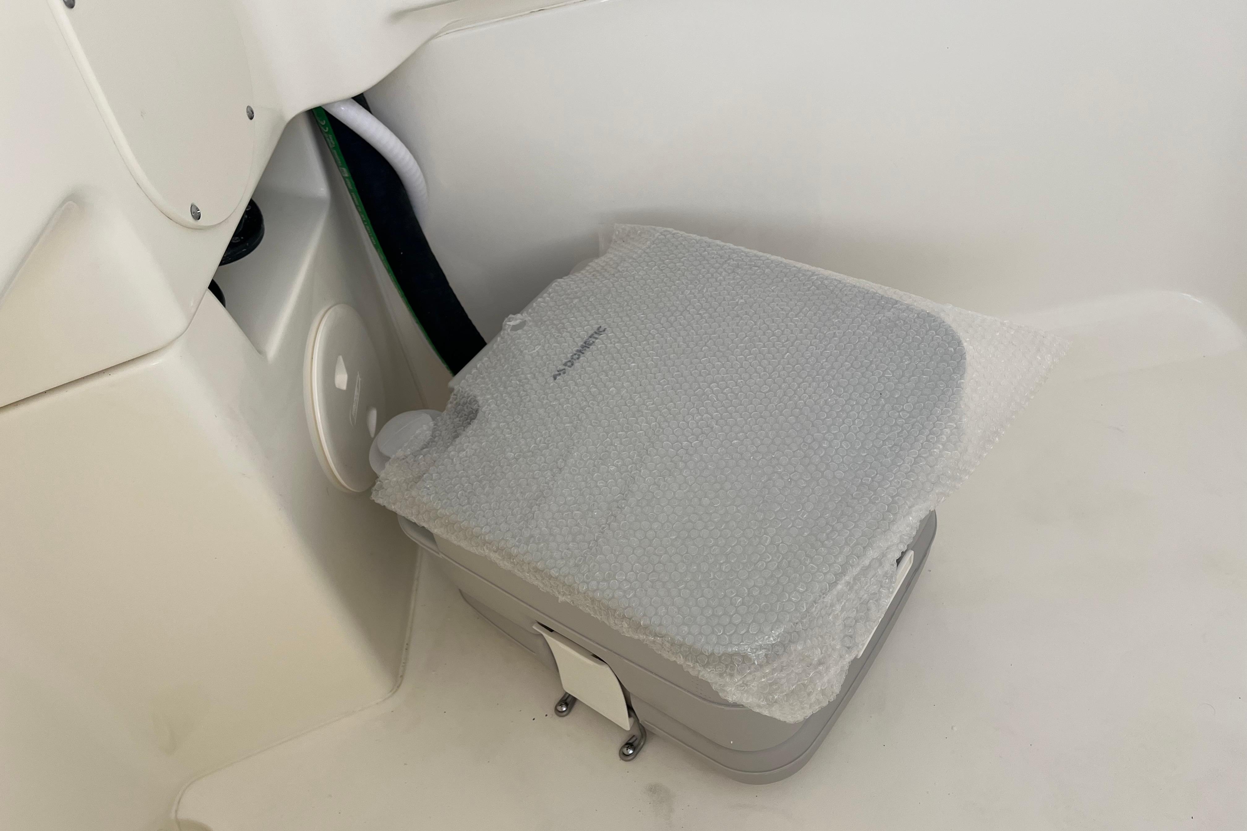 Portable toilet in 2026 Boston Whaler 280 Dauntless boat, covered with bubble wrap.
