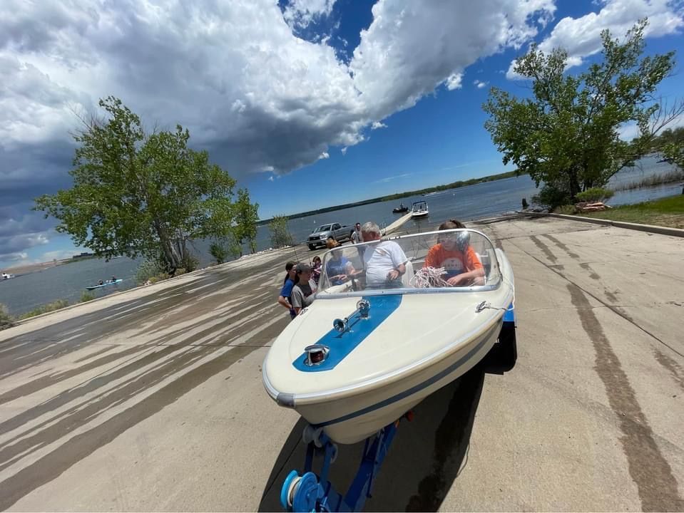 1962 Larsen 13 boat at lakeside with people.