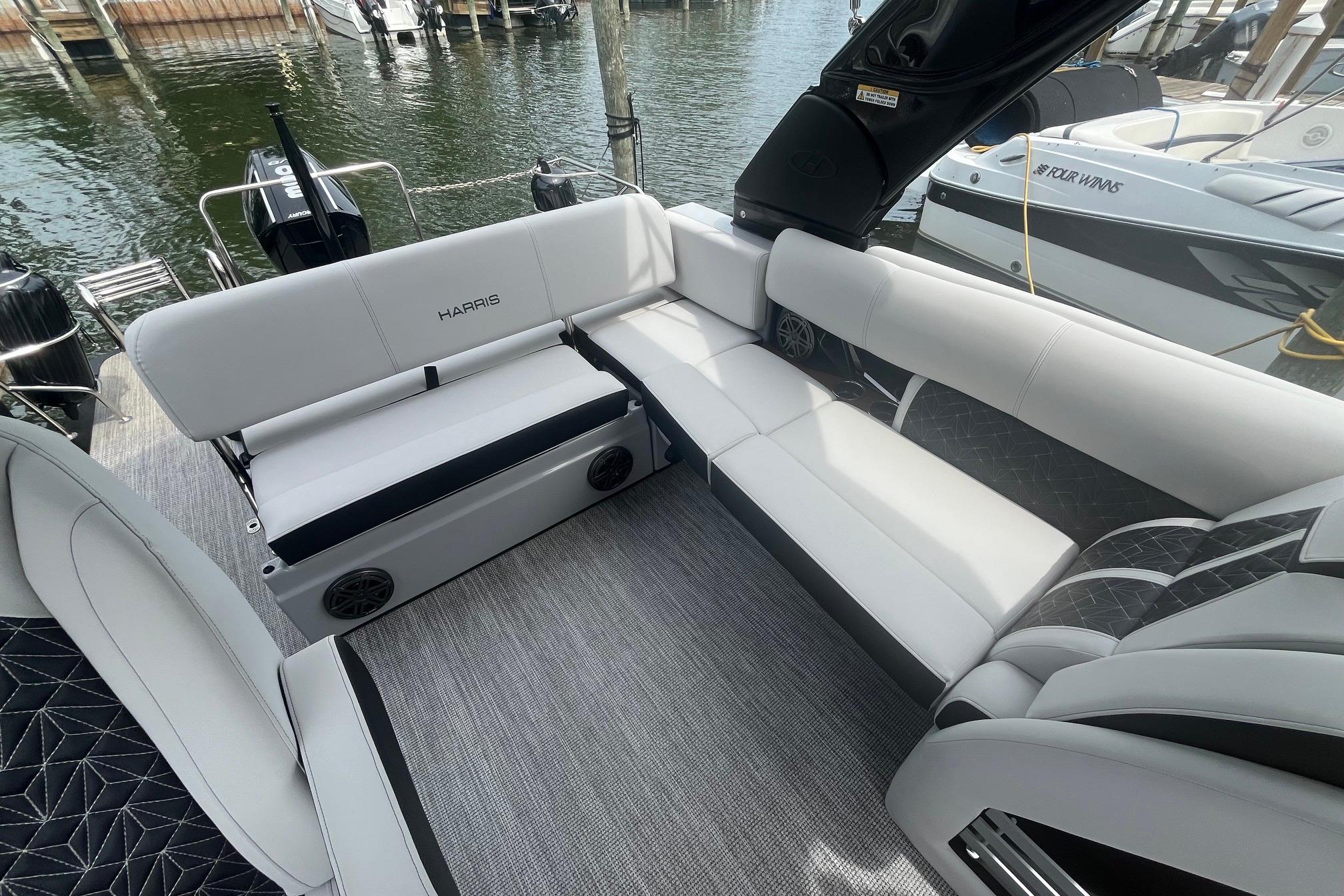 Luxurious seating on 2024 Harris Grand Mariner 250 pontoon boat, docked by the water.