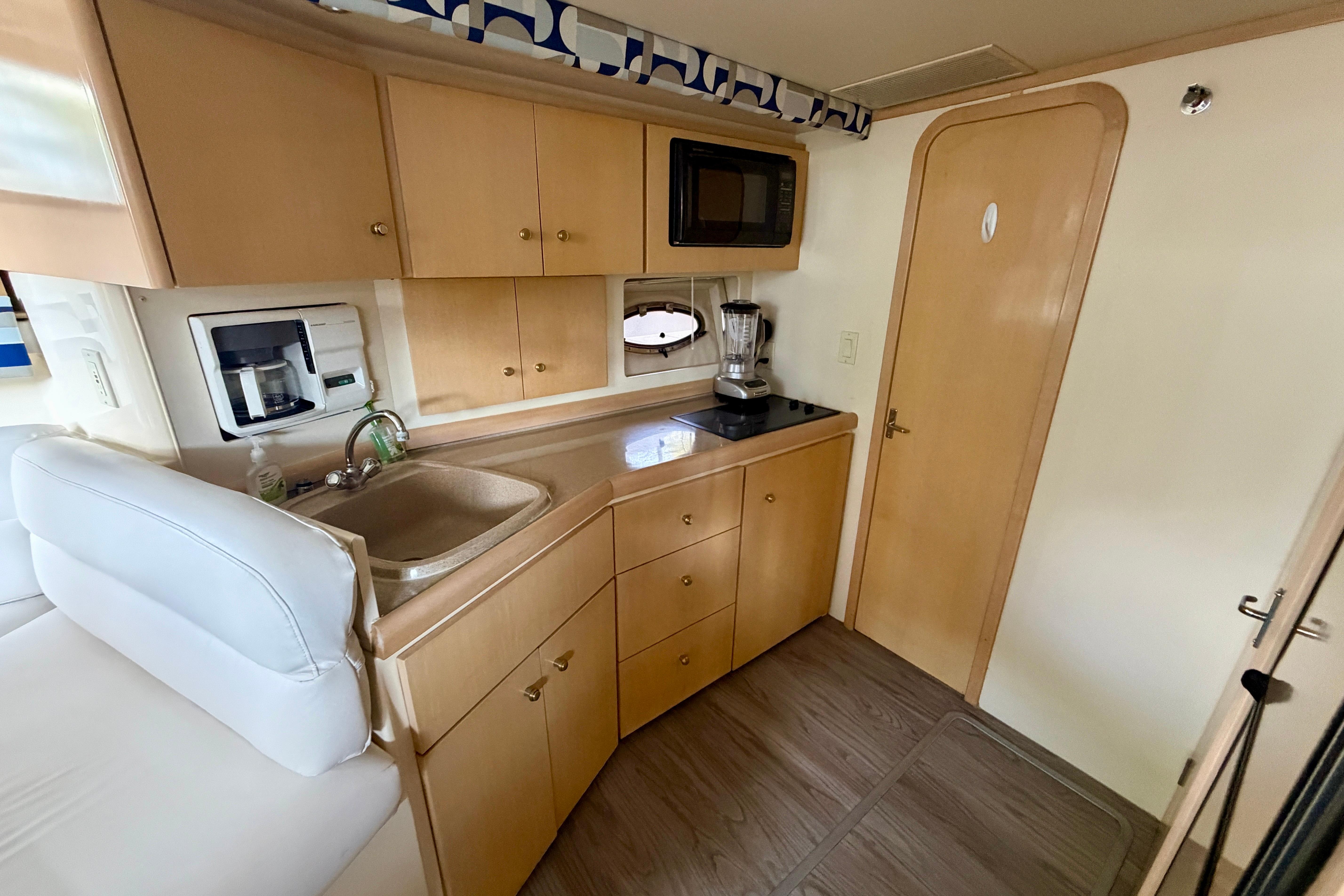 2000 Carver 350 Mariner yacht kitchen with wood cabinets, sink, microwave, and blender.