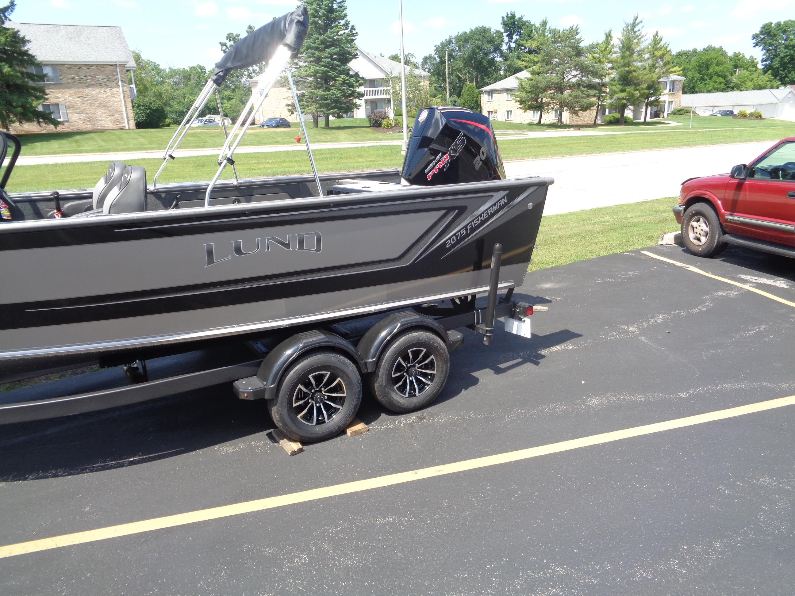 2025 Lund 2075 Fisherman boat on trailer in parking lot, sunny day.
