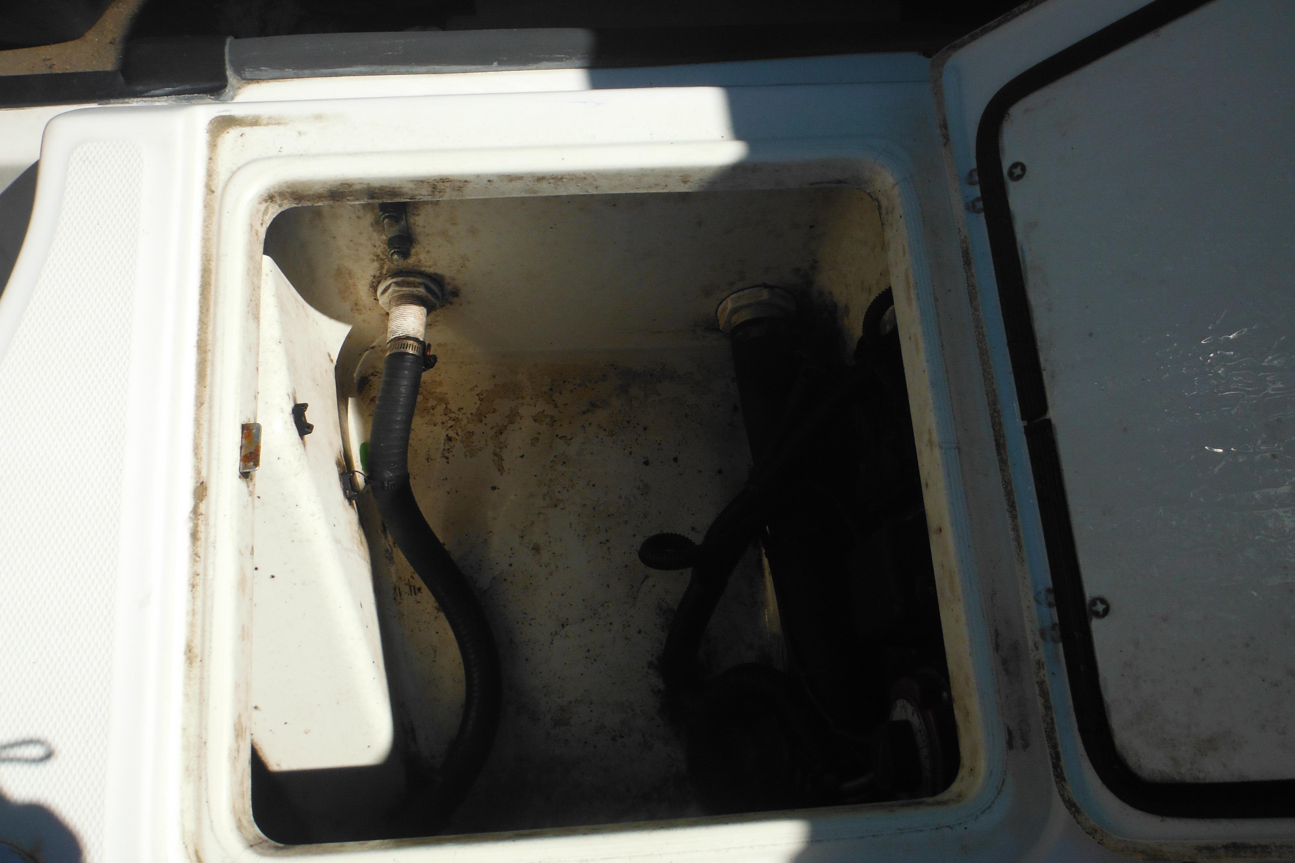 Open storage compartment on a 2009 Boston Whaler 200 Dauntless boat, showing hoses and fittings.