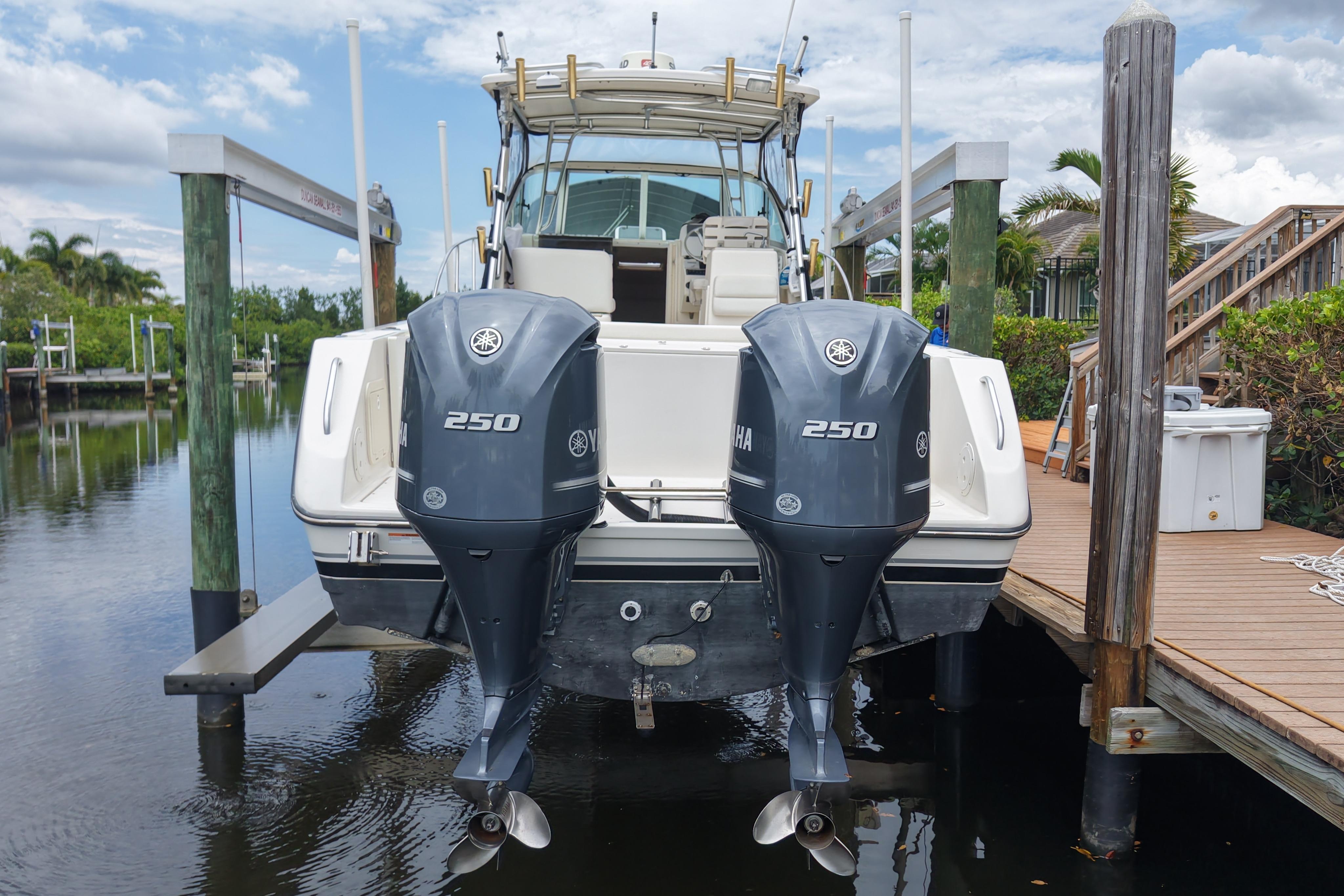 2005 Pursuit 3070 Offshore boat with twin Yamaha 250 engines docked by wooden pier.