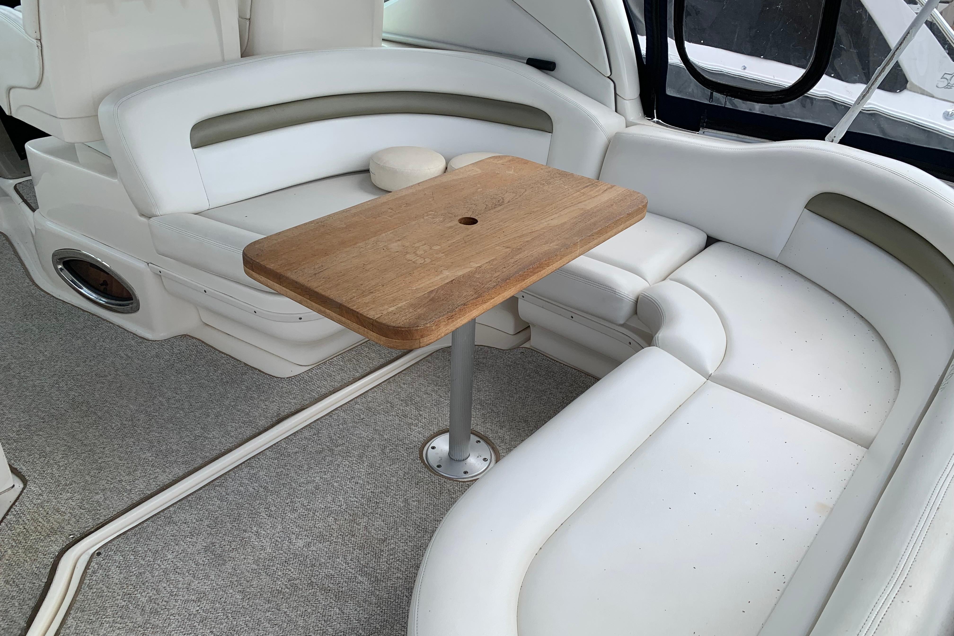 2007 Sea Ray 340 Sundancer interior with white seating and wooden table.