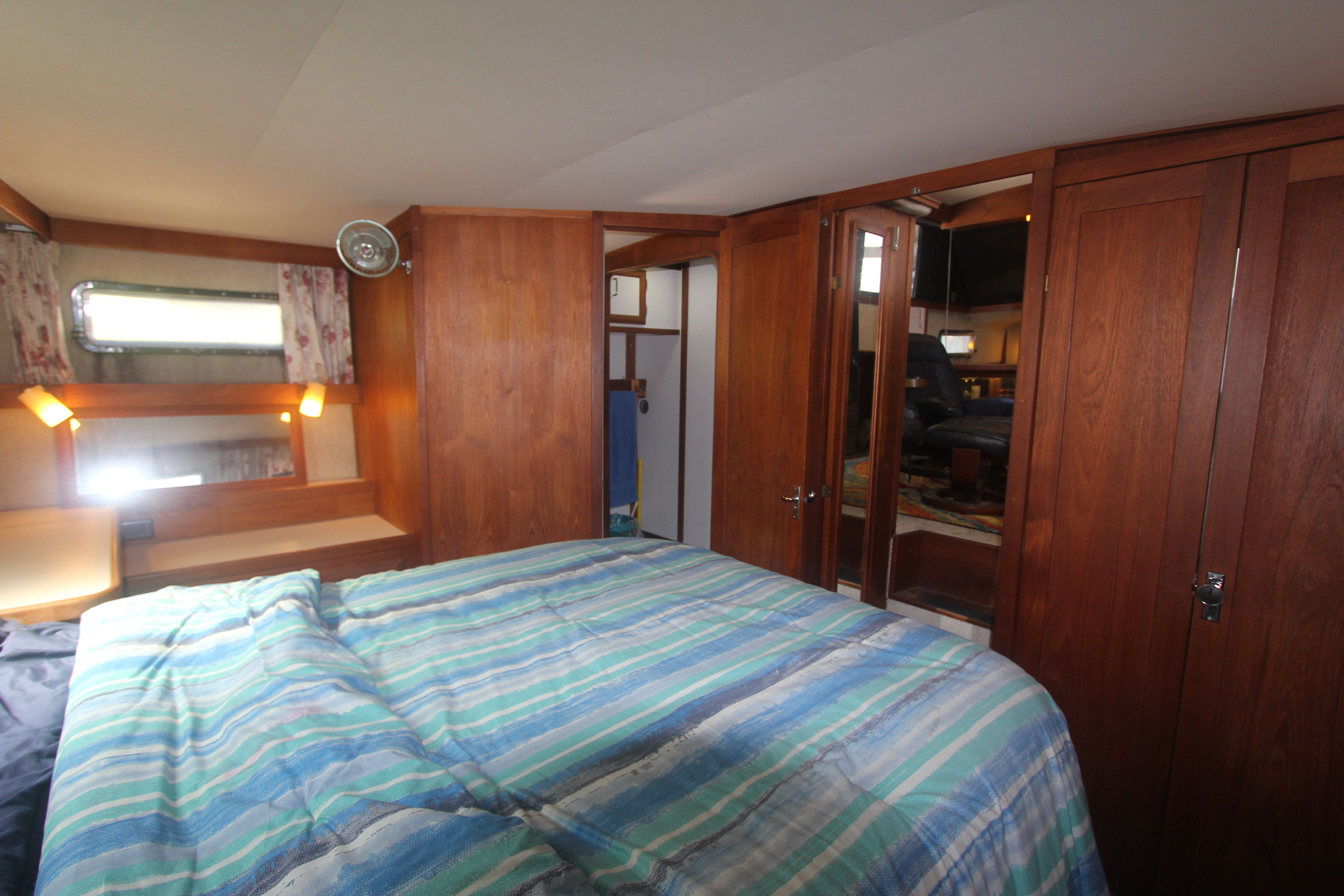 Interior of a yacht featuring a cozy bedroom with wood furnishings and a window.