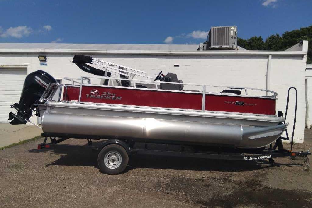 2026 Sun Tracker Bass Buggy 18 DLX pontoon boat on trailer, parked outdoors.