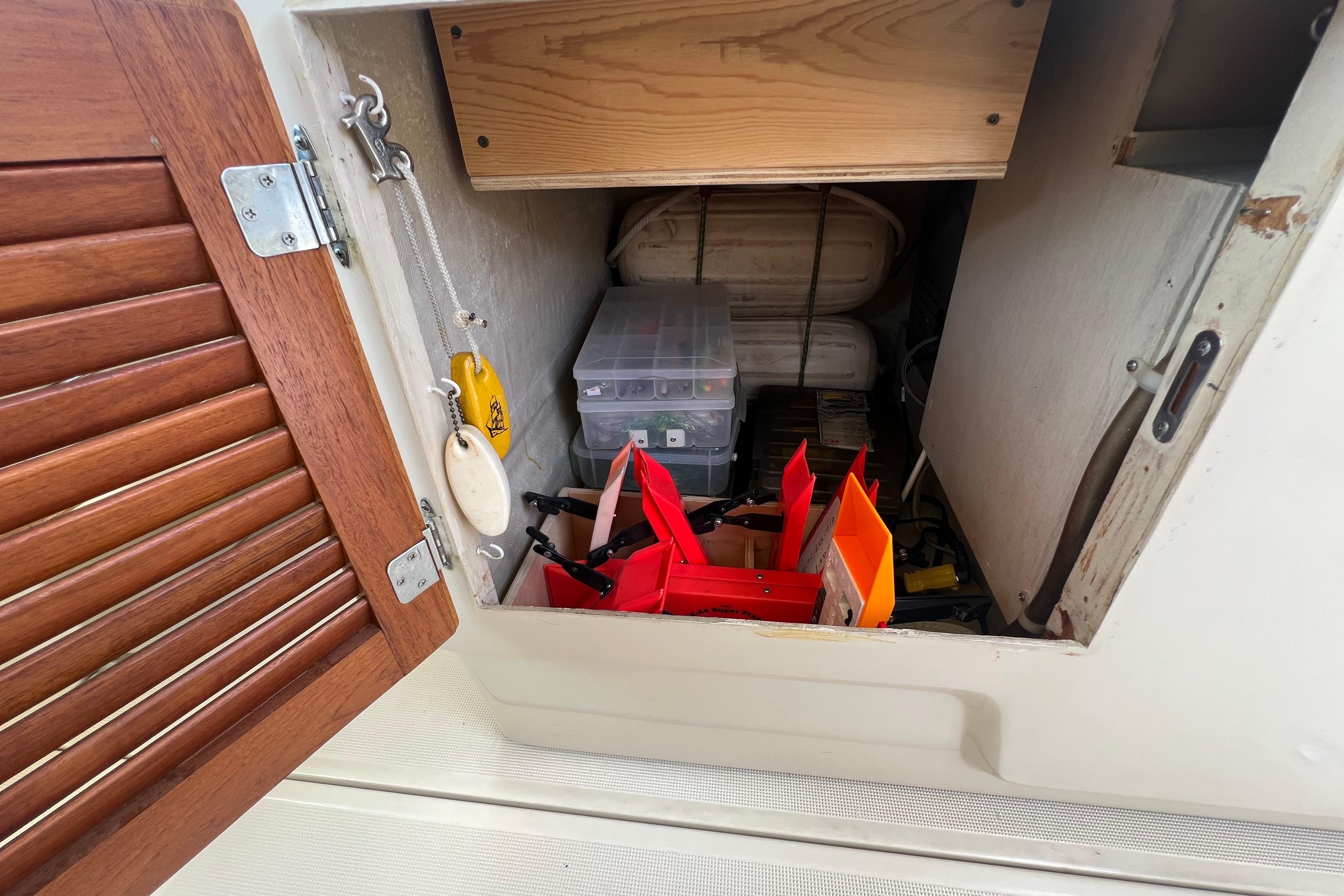 Storage compartment on a 1985 Tiara 36 OPEN boat with tools and equipment.