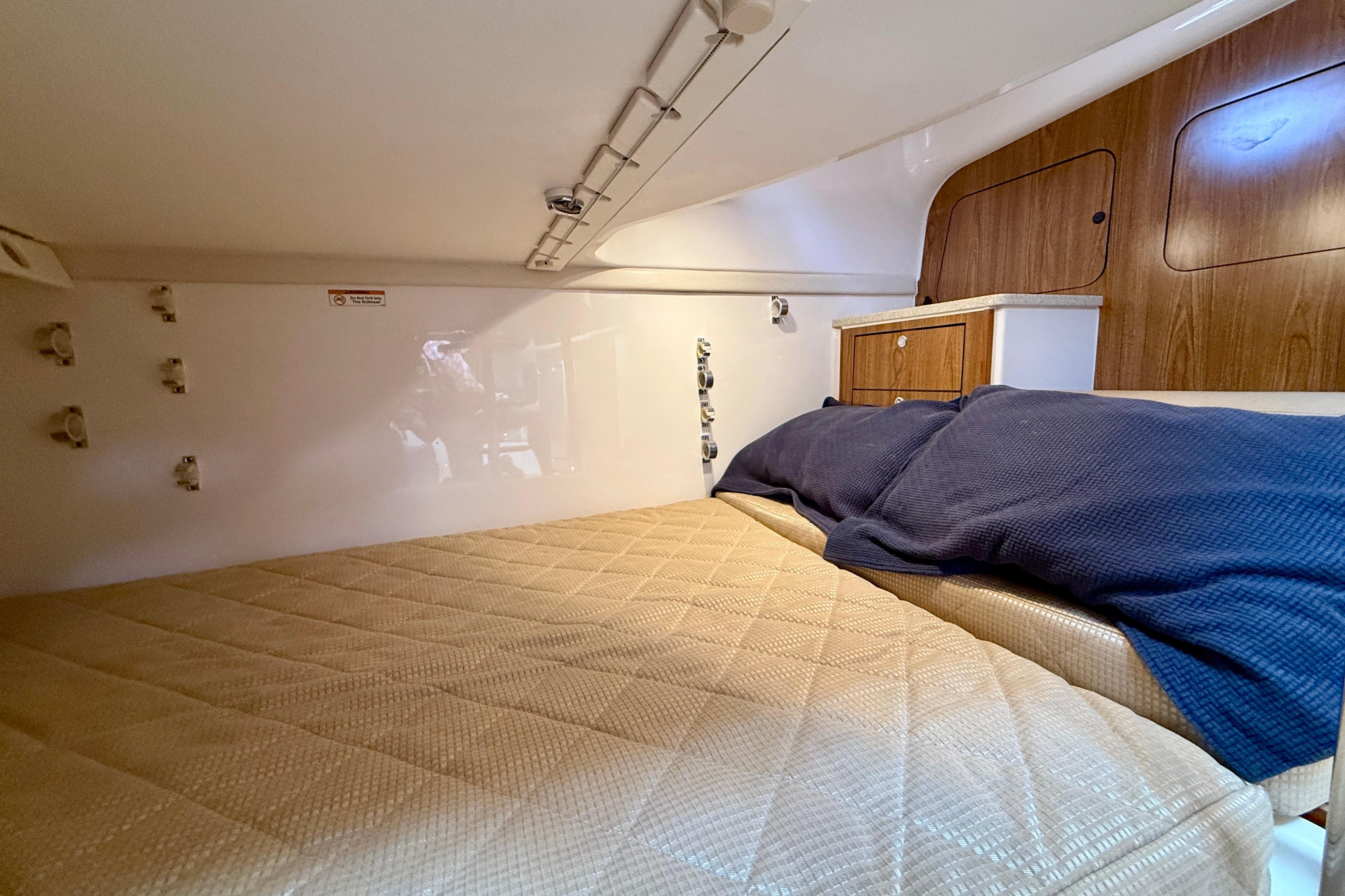 Interior cabin of 2012 Pursuit OS 345 Offshore boat with cozy bedding and wooden cabinetry.