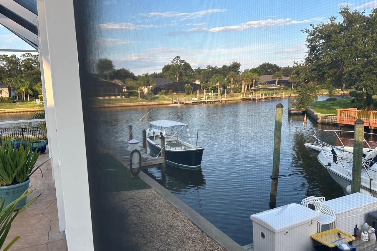 Canal view with boats docked, surrounded by lush greenery and residential homes.