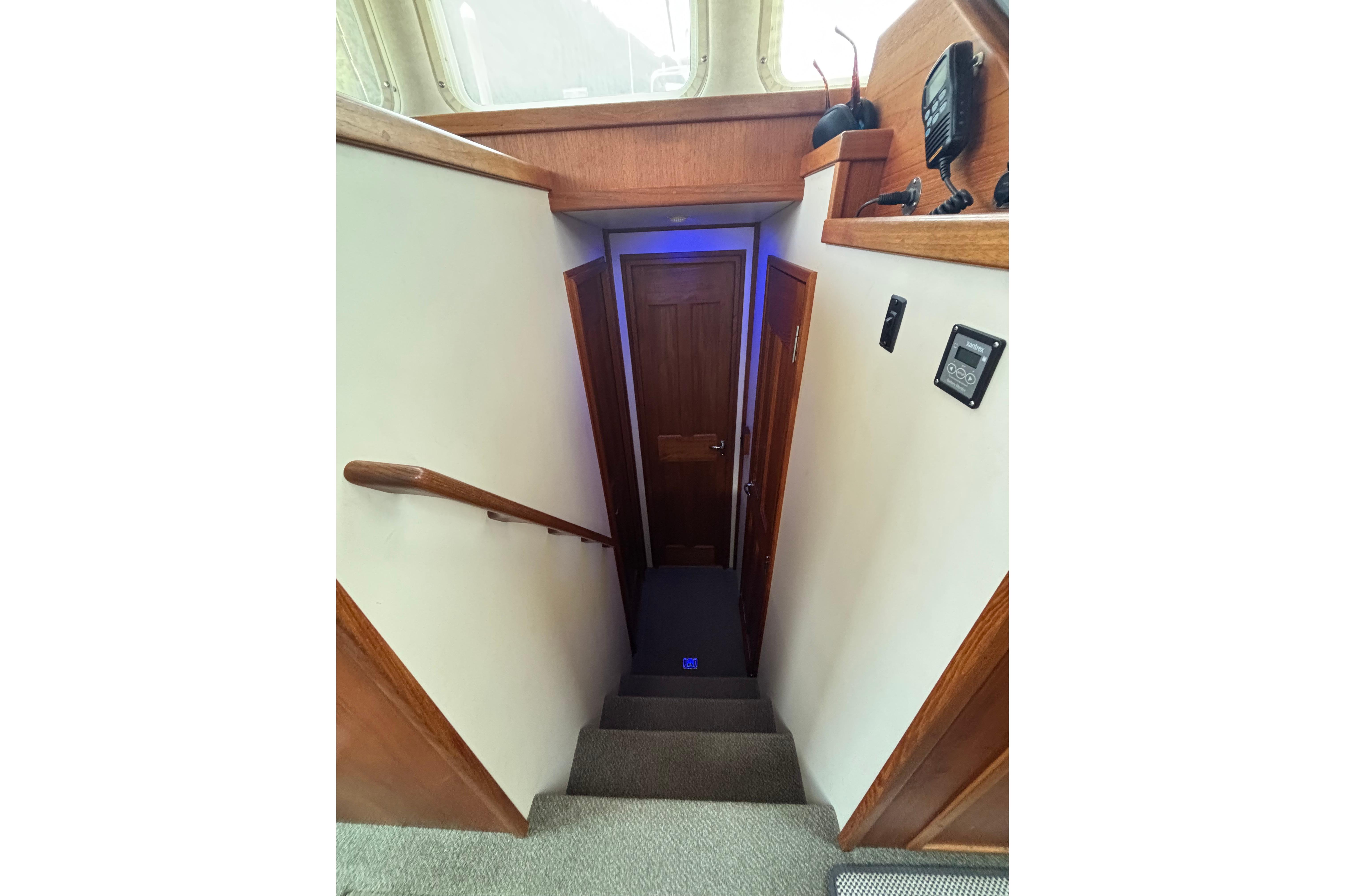 Stairway inside 2004 Nordic Tug 37, featuring wooden accents and modern controls.