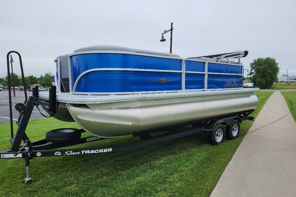 2026 Sun Tracker Party Barge 20 DLX pontoon boat on trailer, parked on grass.