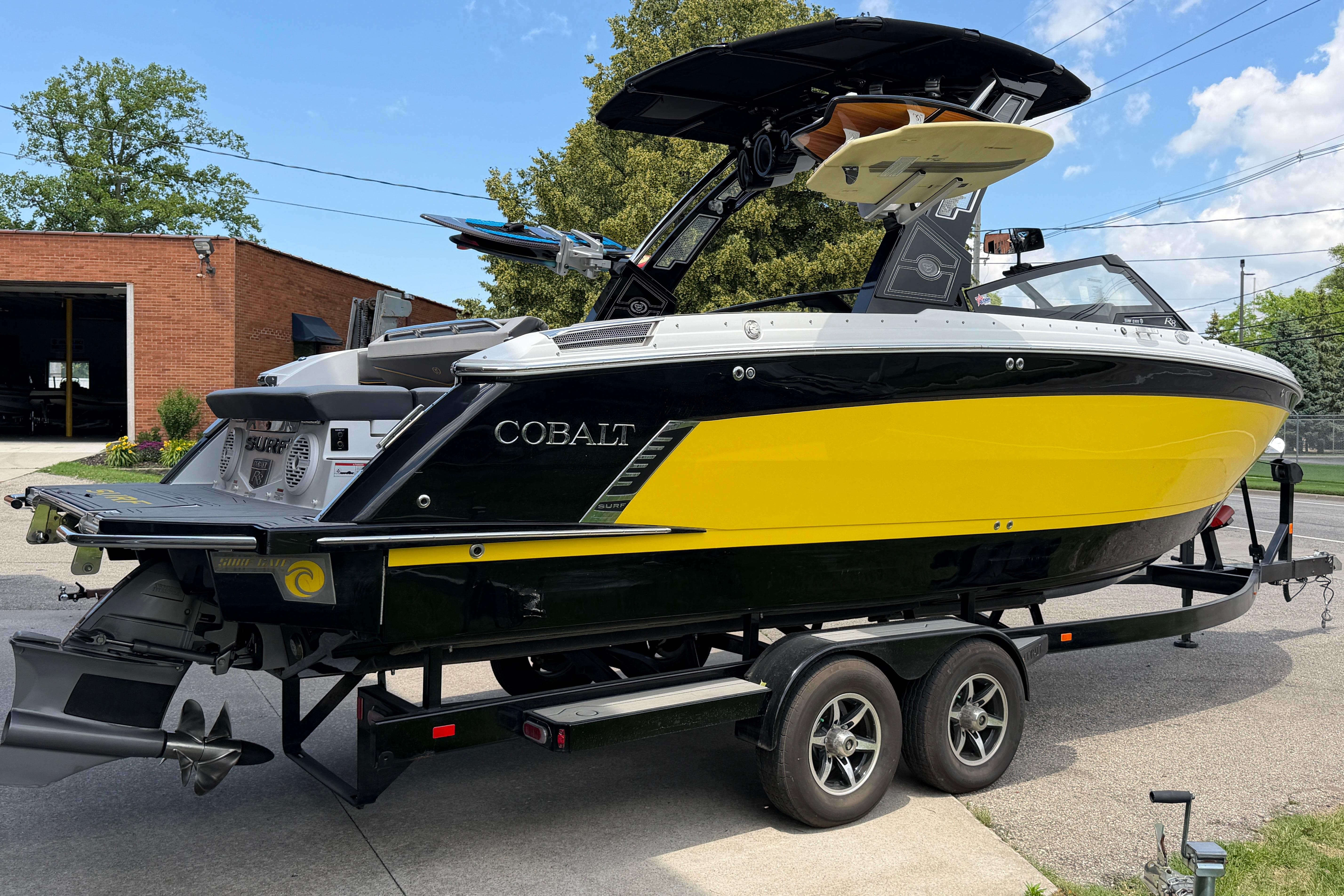 2021 Cobalt R8 Surf boat in yellow and black on a trailer, parked outdoors.