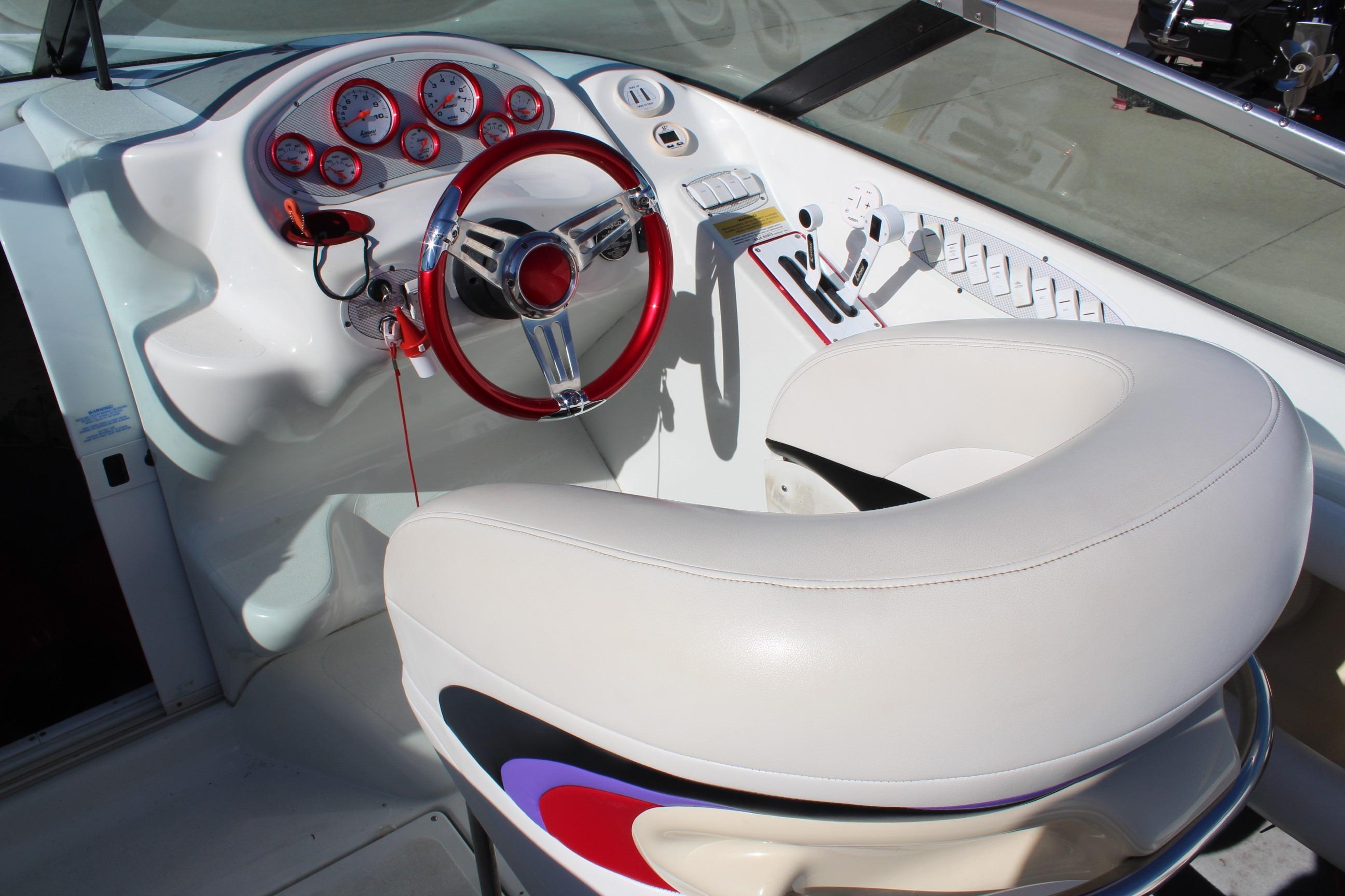 Cockpit of a 1996 Baja 232 boat with red steering wheel and white seating.