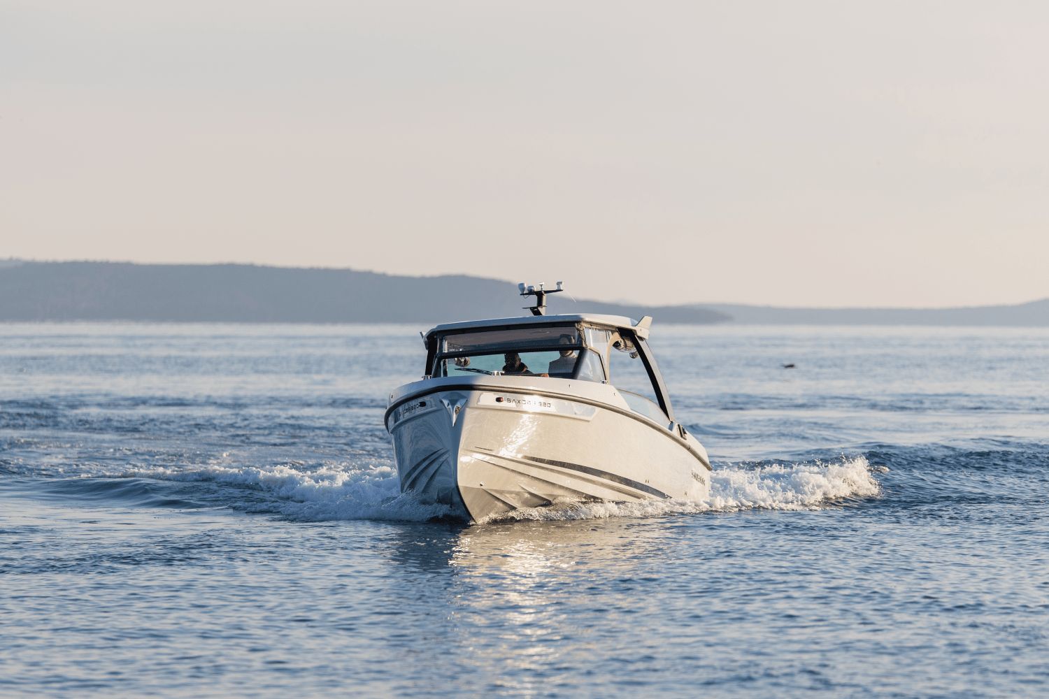 A Saxdor SX320 GTO boat cruising on calm water at sunset.