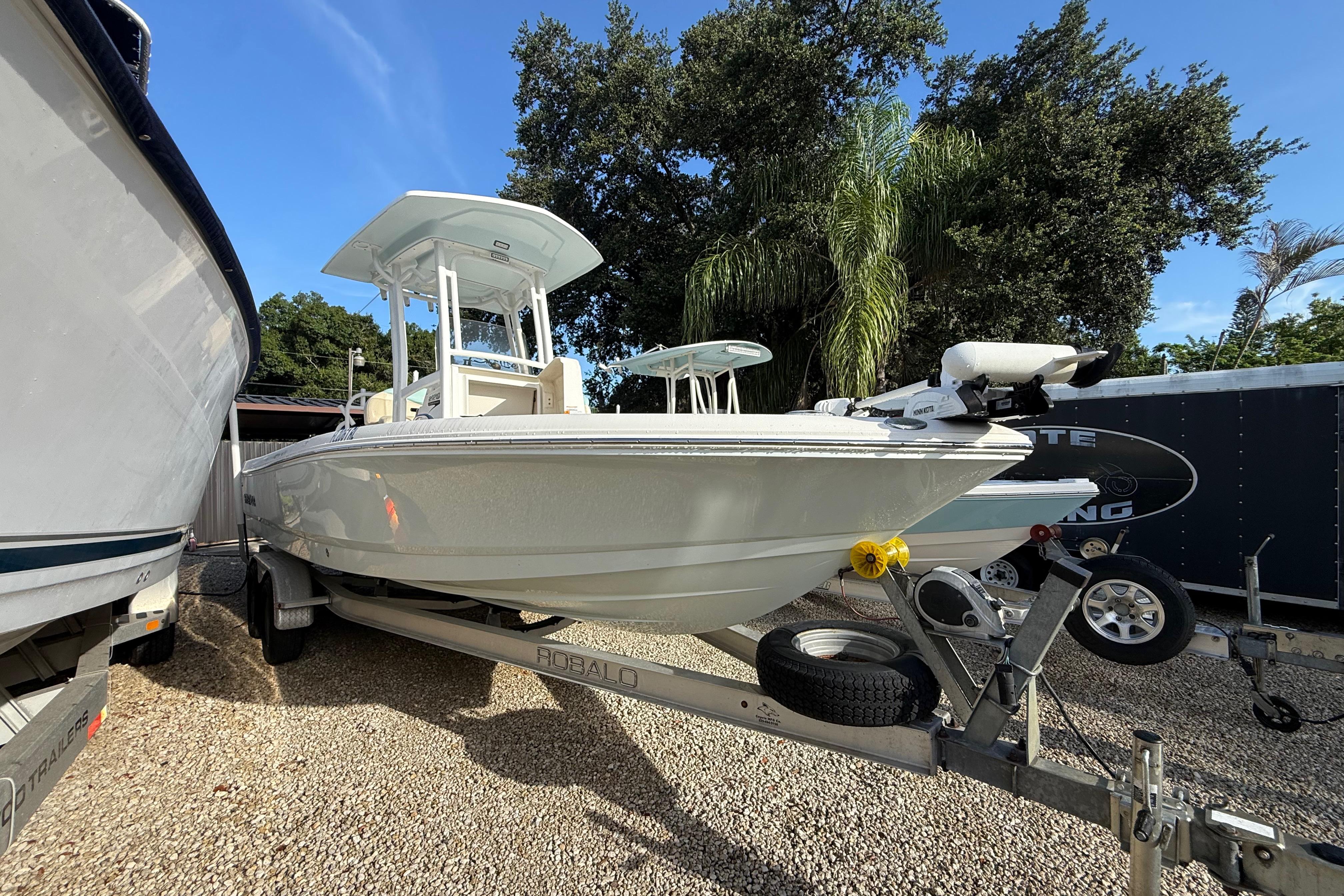 2017 Robalo 226 Cayman boat on trailer, parked outdoors with trees in background.
