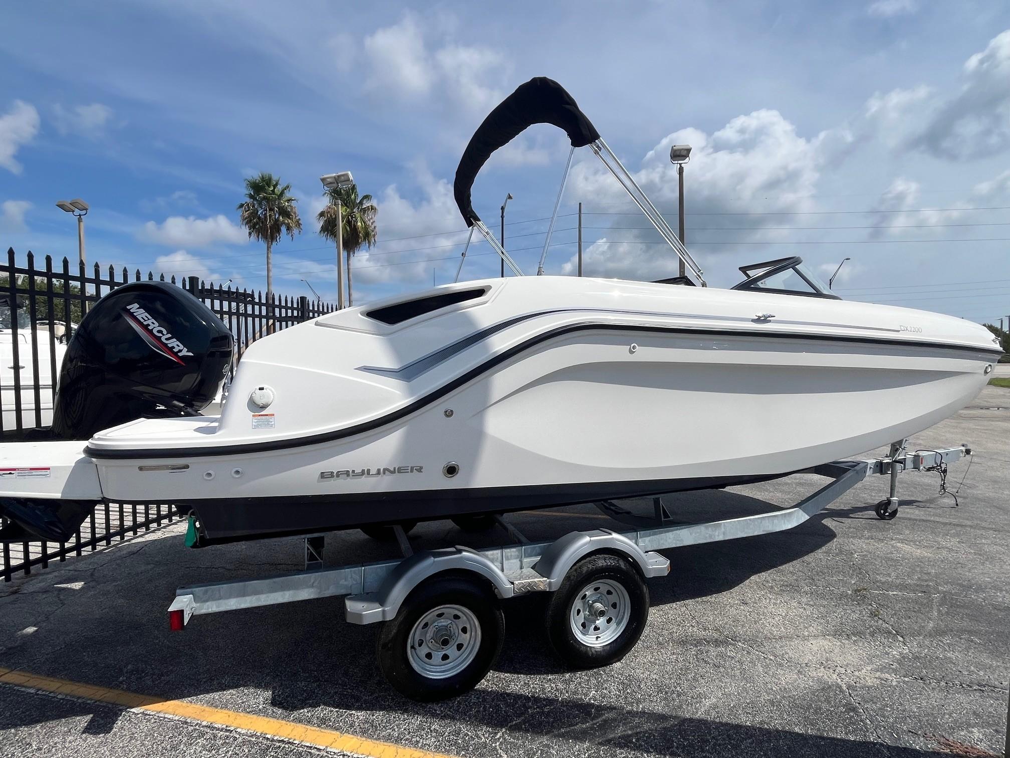 2022 Bayliner DX 2200 boat on trailer, parked outdoors under a clear sky.