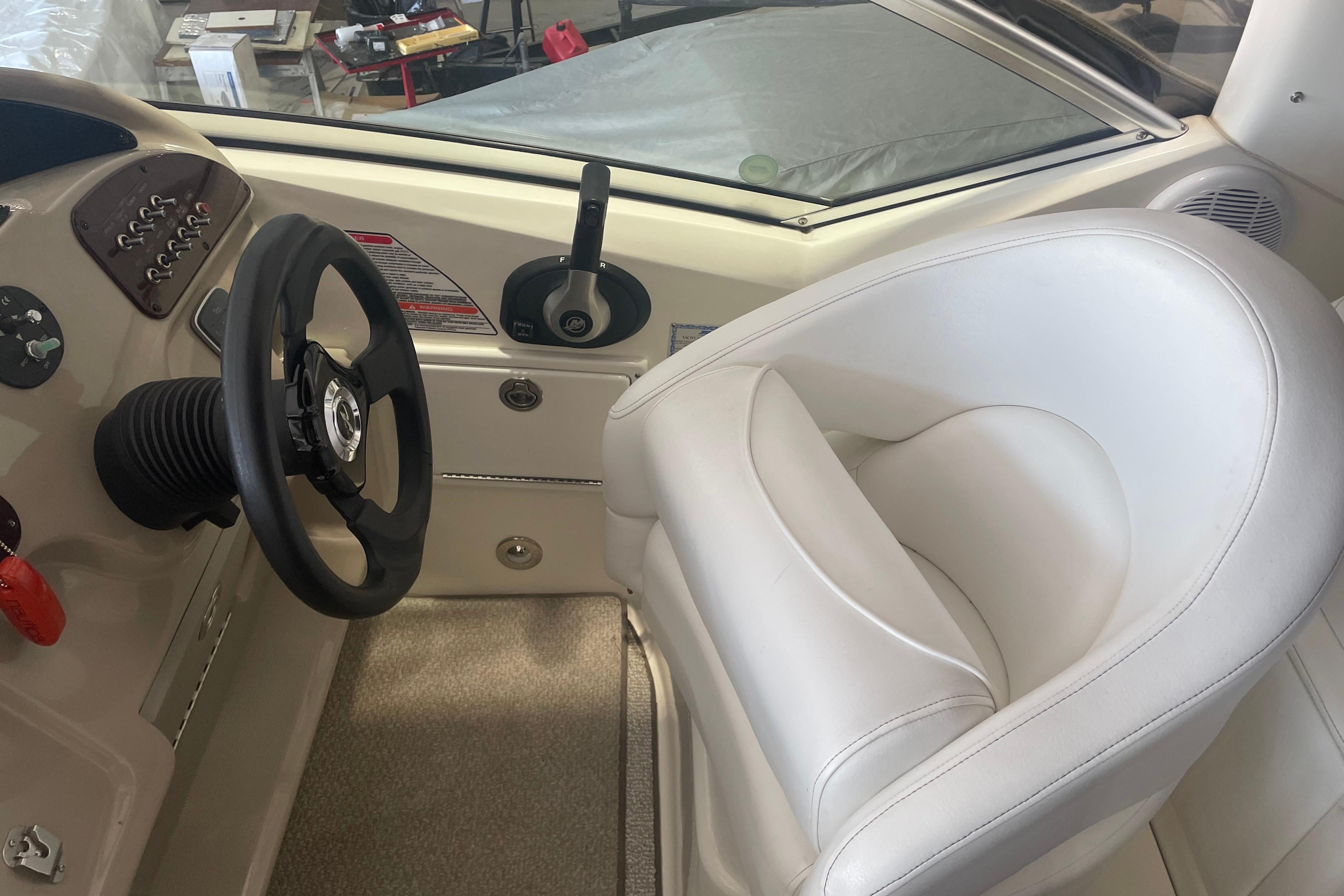 Interior helm of 2006 Sea Ray Sundancer 260 with steering wheel and white captain's chair.