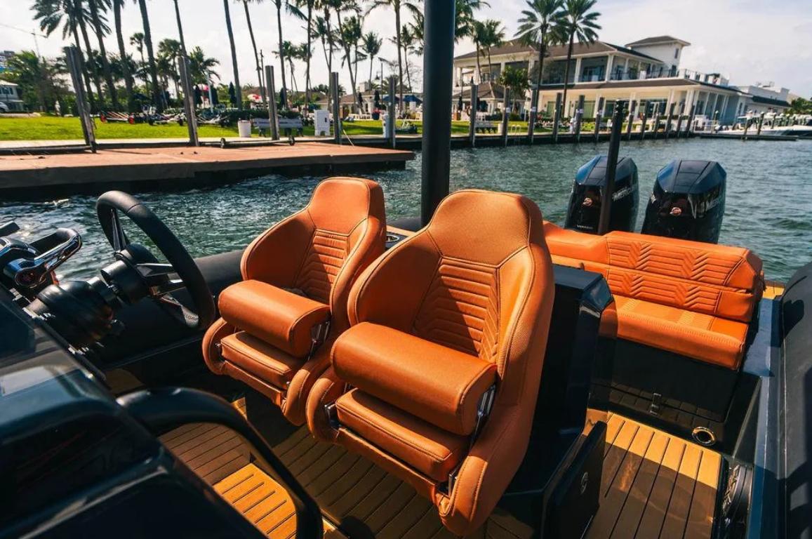 Luxurious 2025 Onda Magna boat interior with orange leather seats and scenic waterfront view.