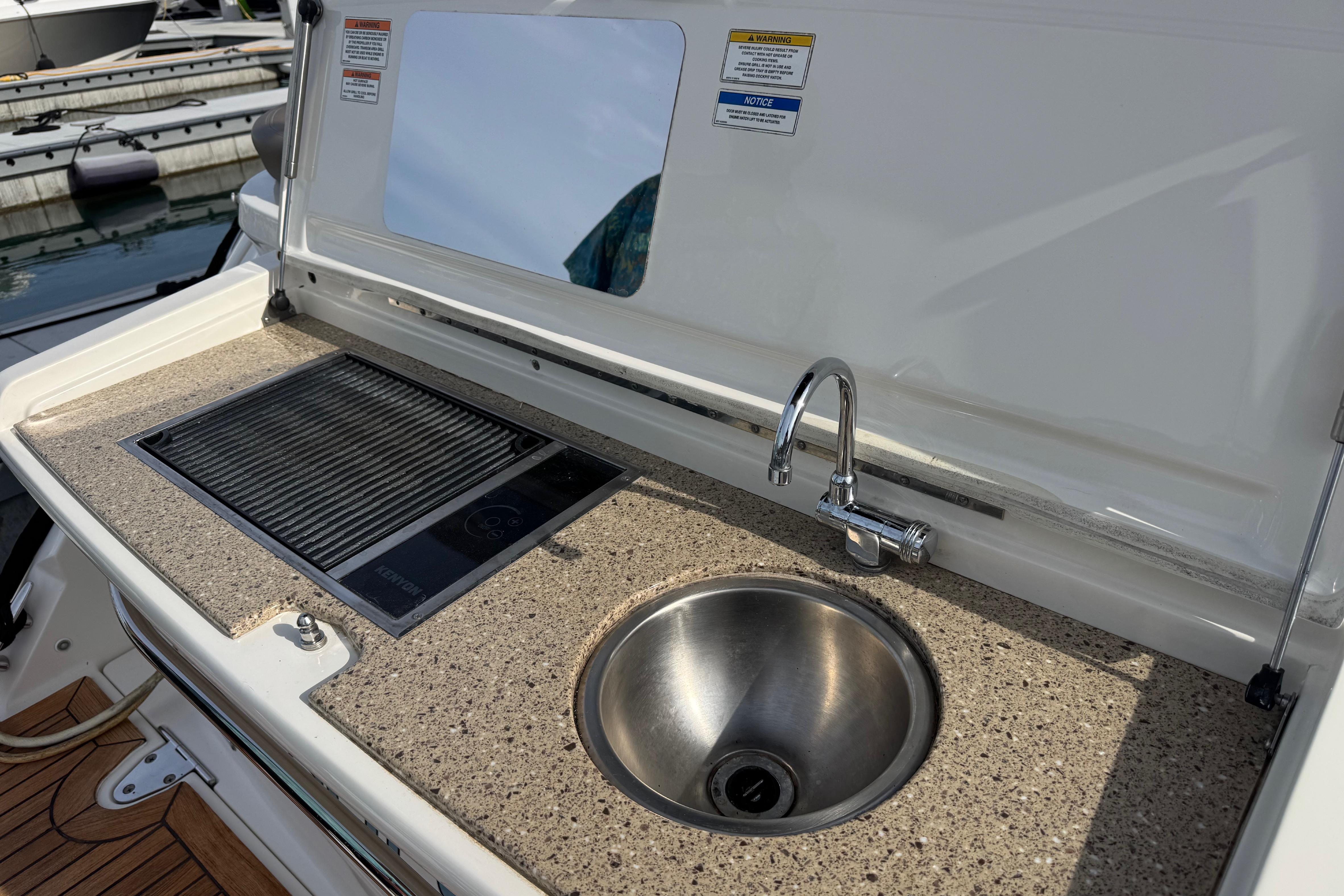 Outdoor kitchenette on a 2016 Sea Ray Sundancer 350 yacht with sink and grill.
