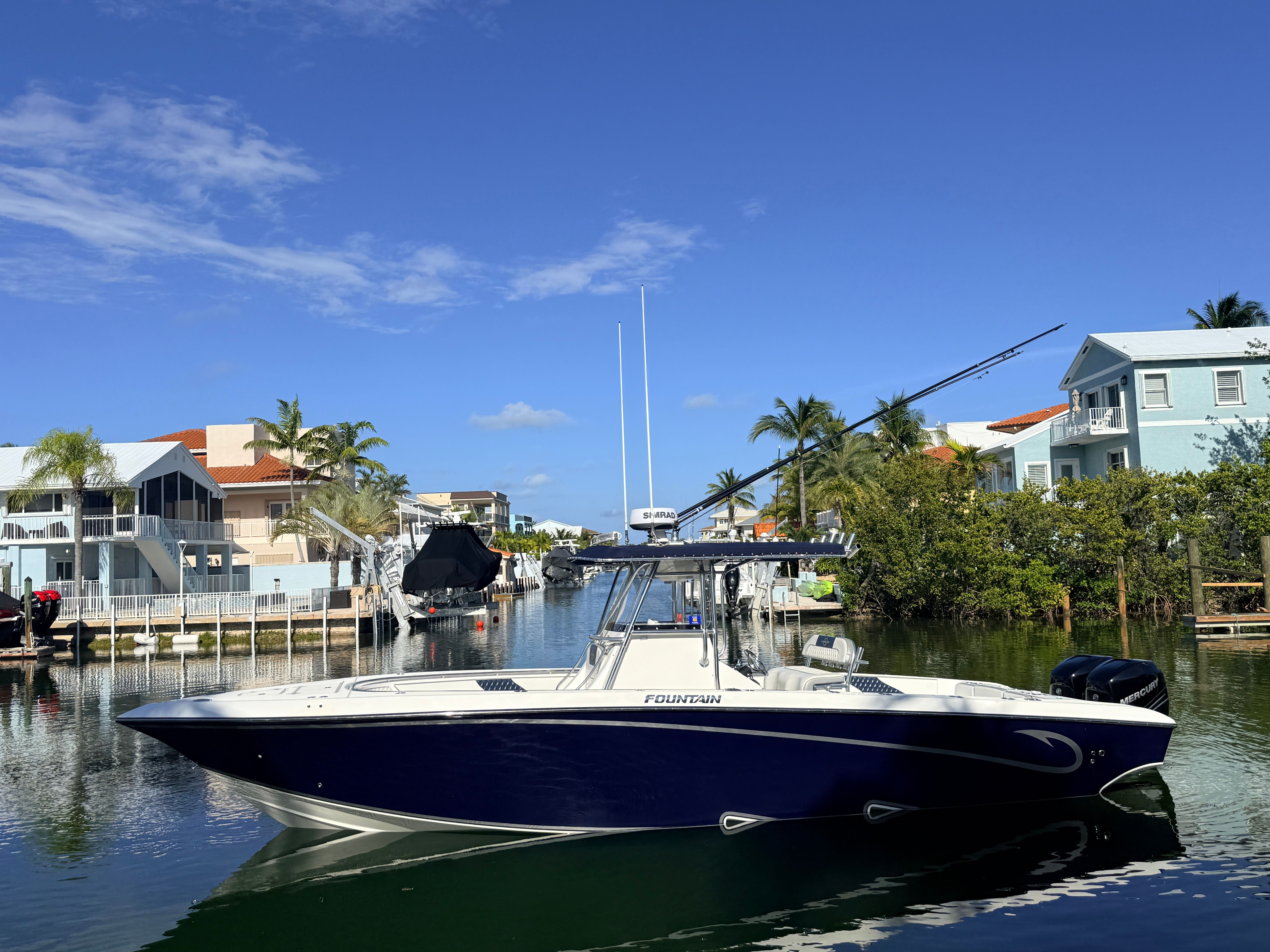 2007 Fountain 32 Center Console boat in canal with houses.