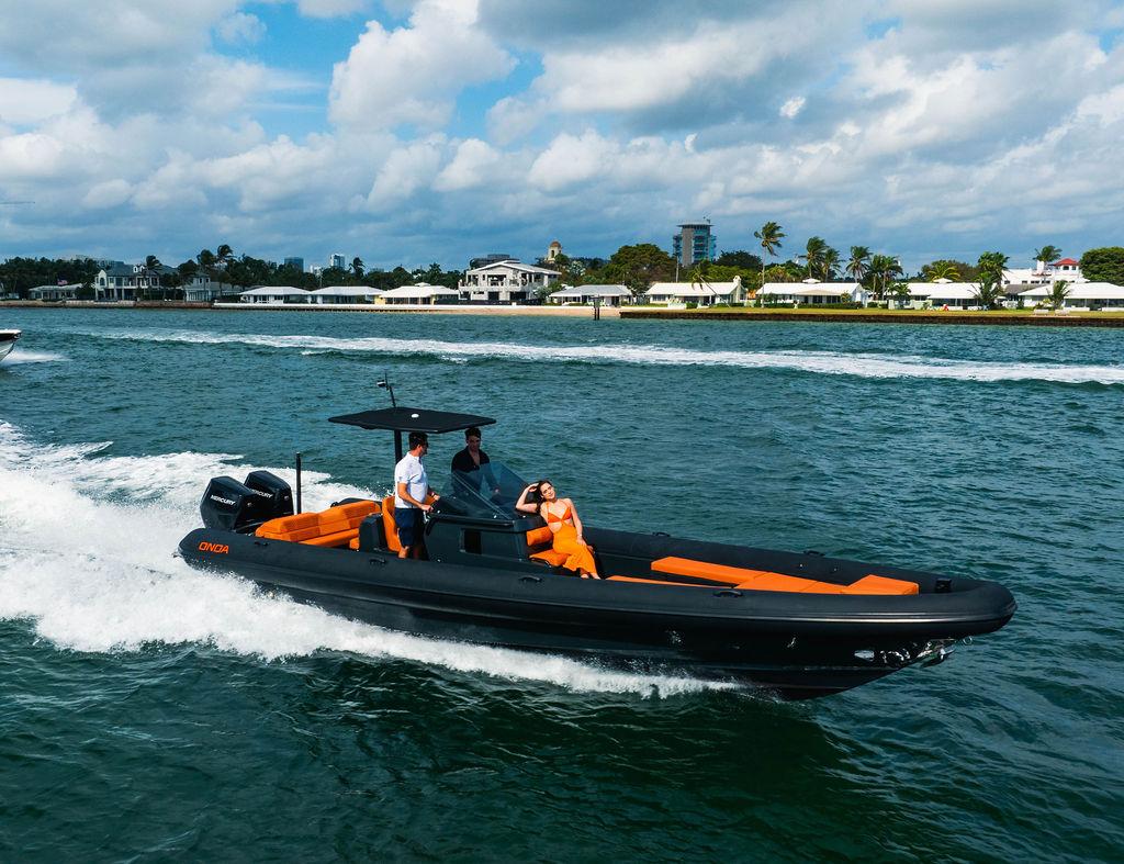 2025 Onda Magna boat cruising on water with passengers, vibrant orange seating, and scenic background.