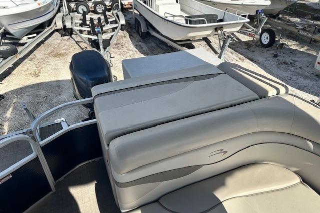 2015 Bennington 21gs pontoon boat with cushioned seating, parked among other boats.