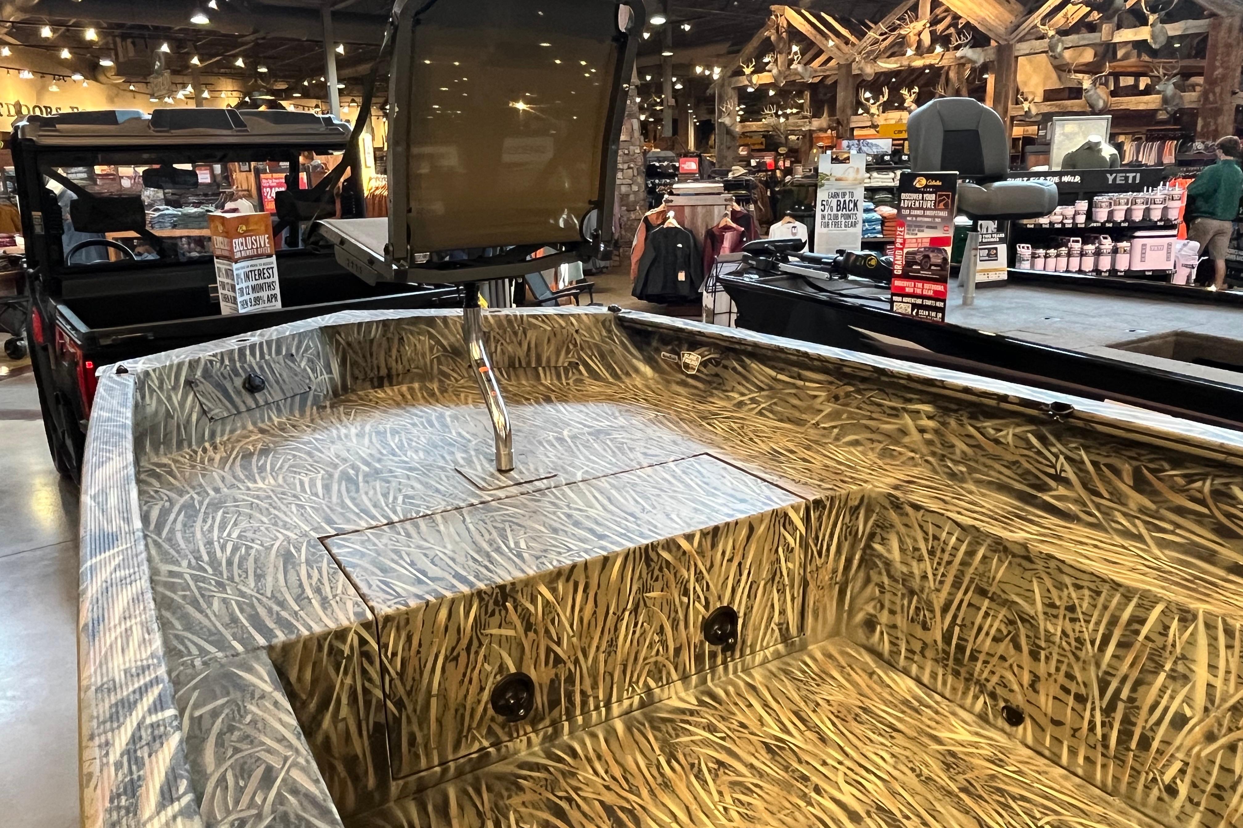 2026 Tracker Grizzly 1650 T Prairie Wings Edition boat with camouflage design in a showroom.