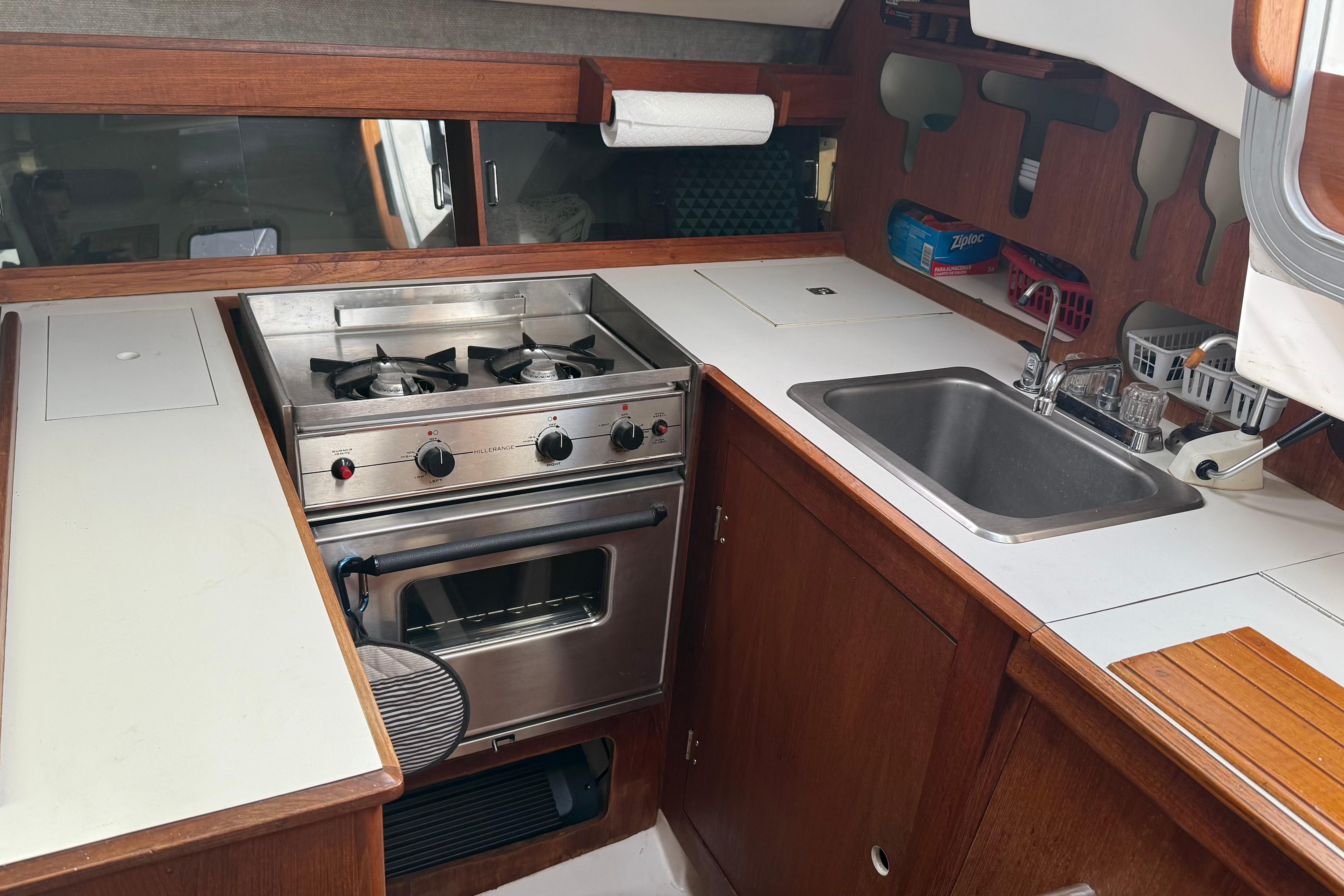 1984 Hunter 31 yacht kitchen with stove, sink, and wooden cabinetry.
