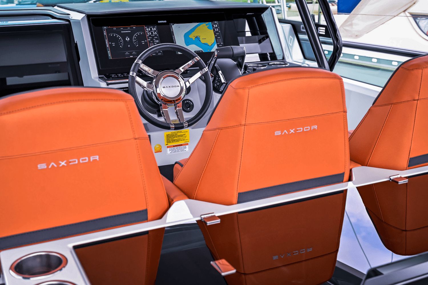 The image shows the cockpit of a Saxdor SX320 GTO with orange seats and a modern helm.