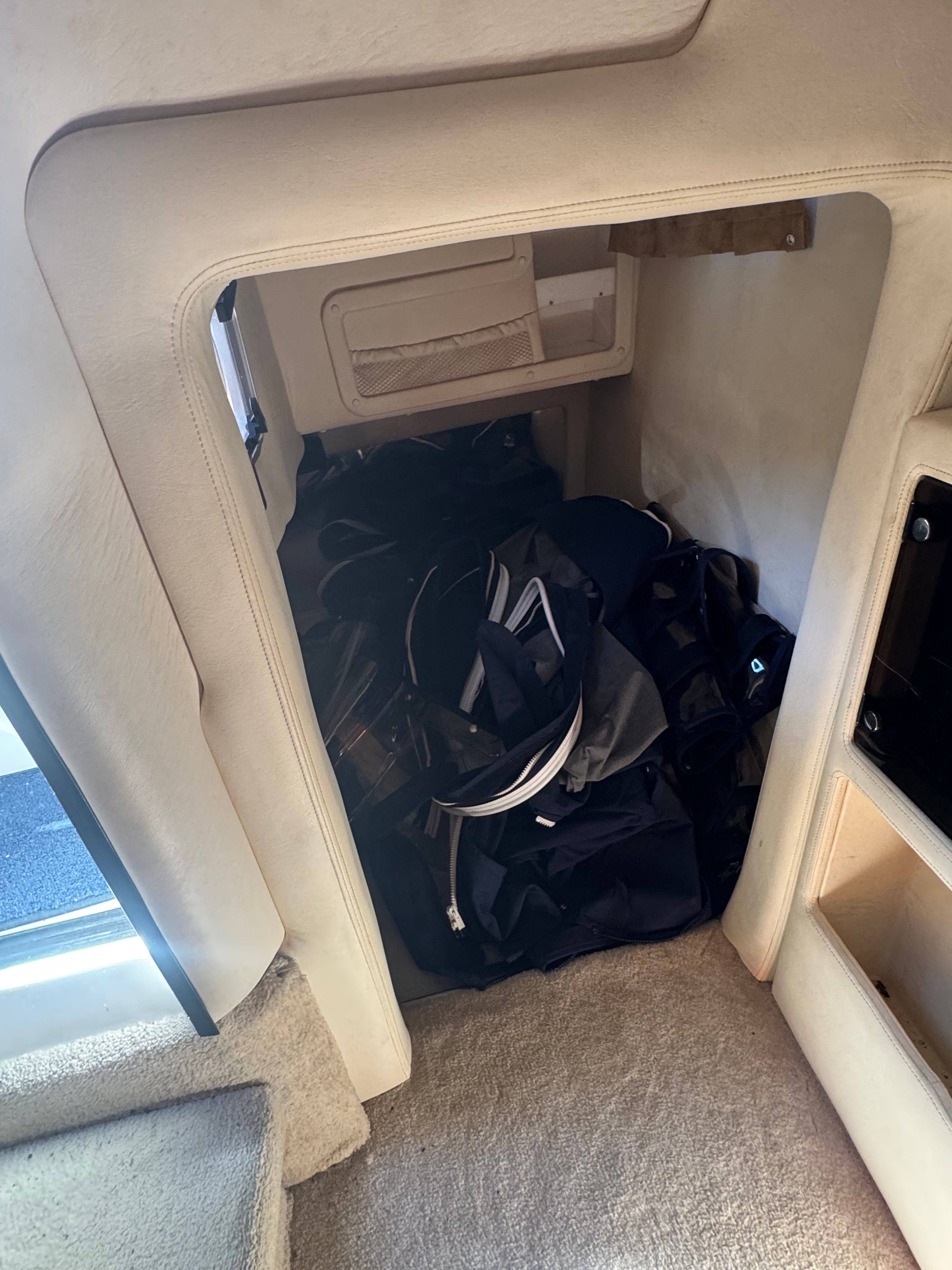 A storage compartment inside a boat with bags and cables.