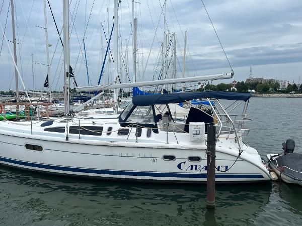 A 2000 Hunter 410 sailboat docked in a marina, featuring a blue canopy.